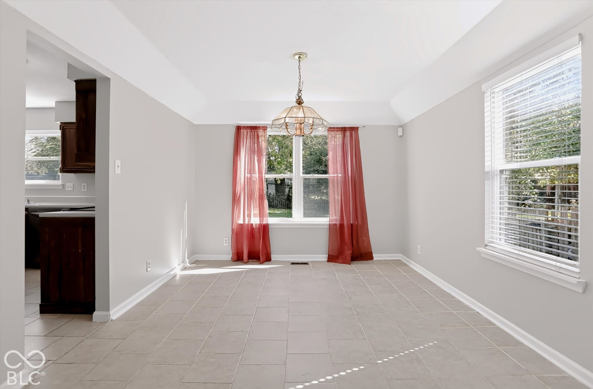 Recessed ceiling detail, tile flooring, central light fixture, two windows with blinds, and white trim molding