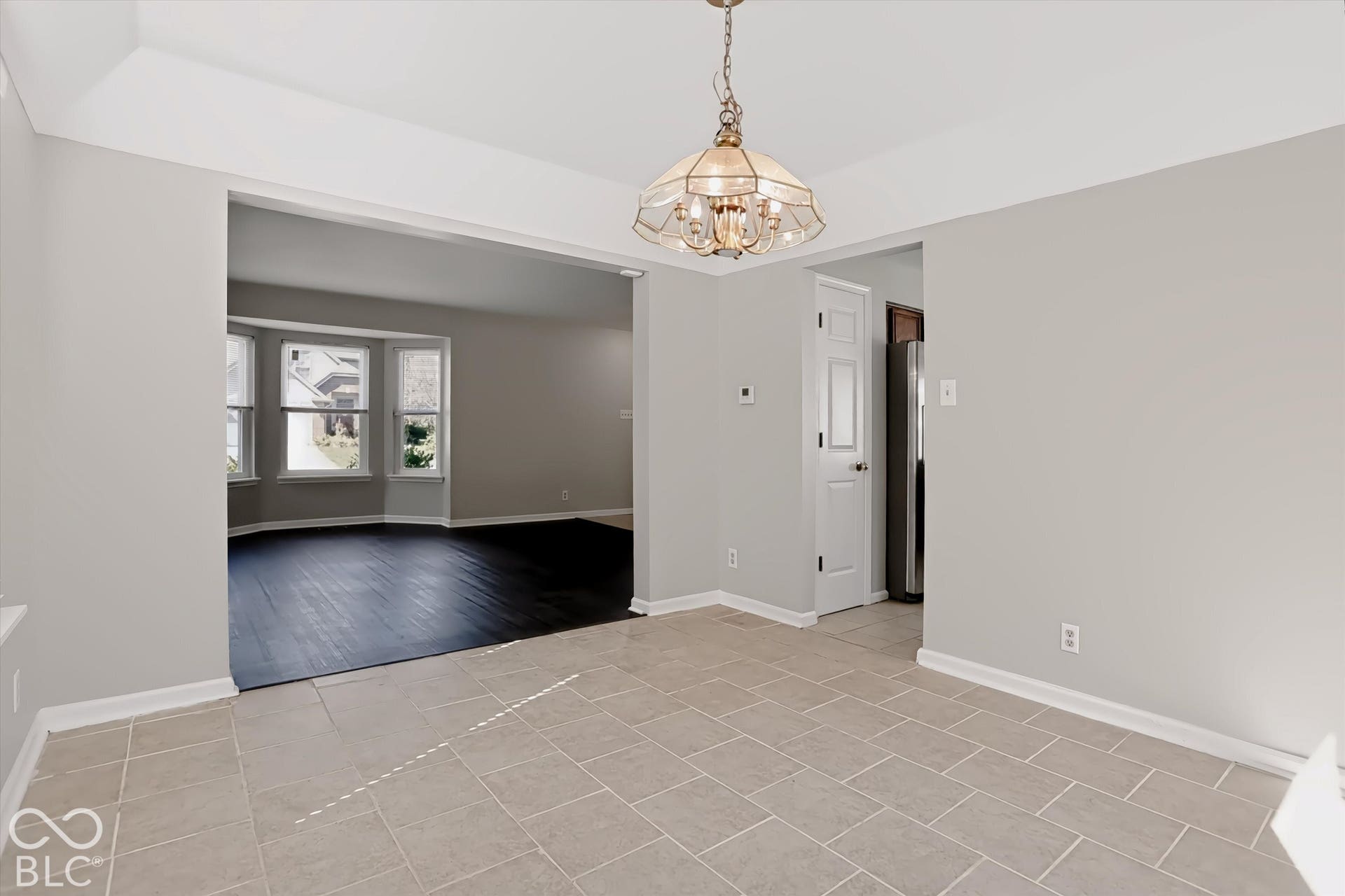 Recessed ceiling lighting, tiled flooring, chandelier lighting fixture, bay window, and dark wood-finish flooring