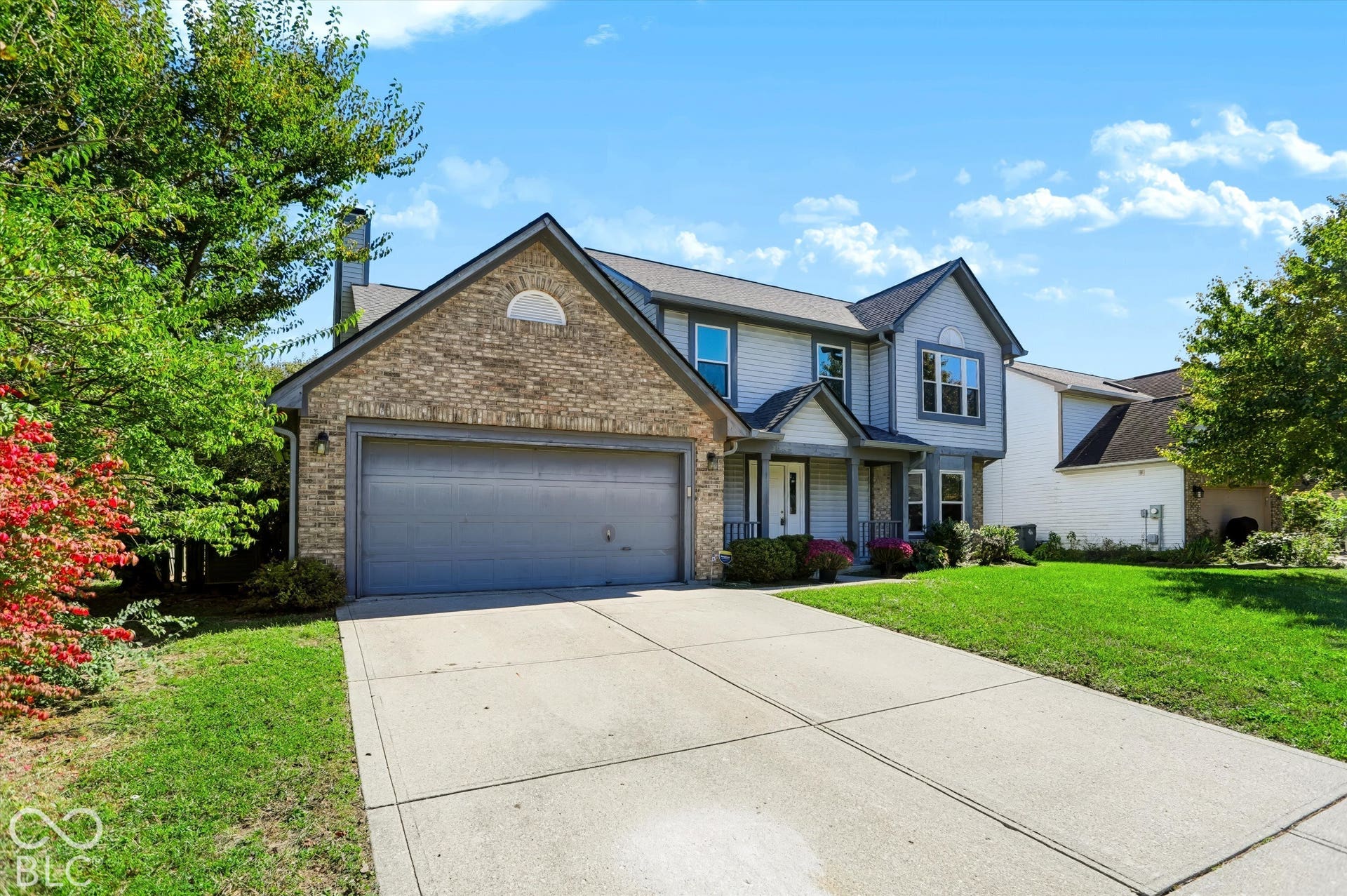 Two-story residence featuring a brick and siding exterior, attached two-car garage, concrete driveway, and covered front entry