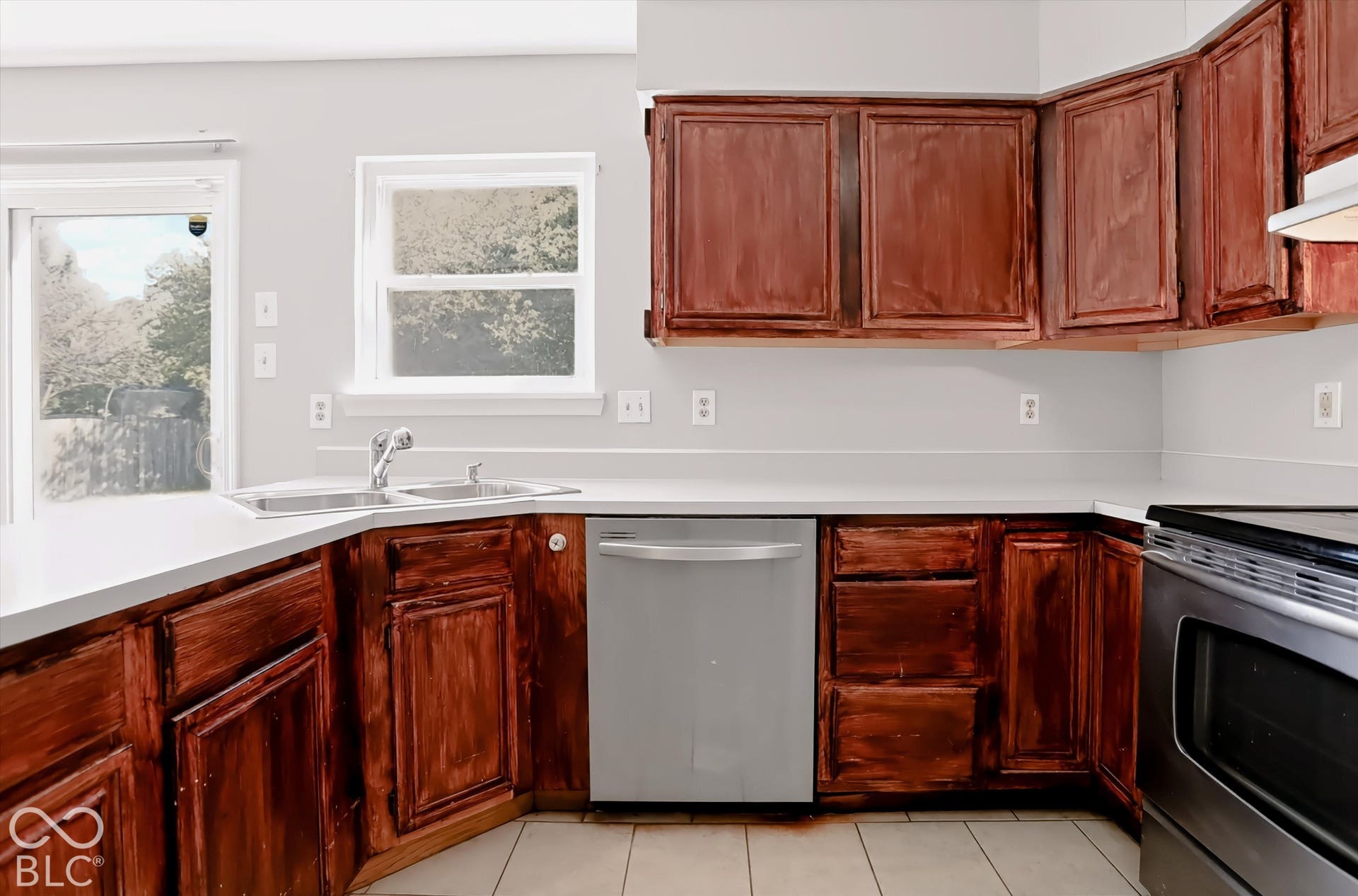 Kitchen featuring wood-finish cabinetry, white countertops, a stainless steel dishwasher, and a stainless steel range