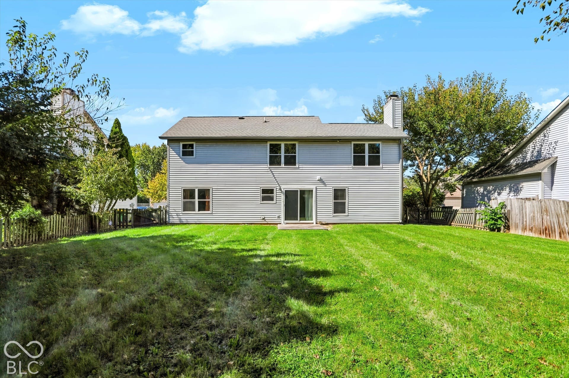 Expansive backyard with a manicured lawn, full fencing, and mature trees