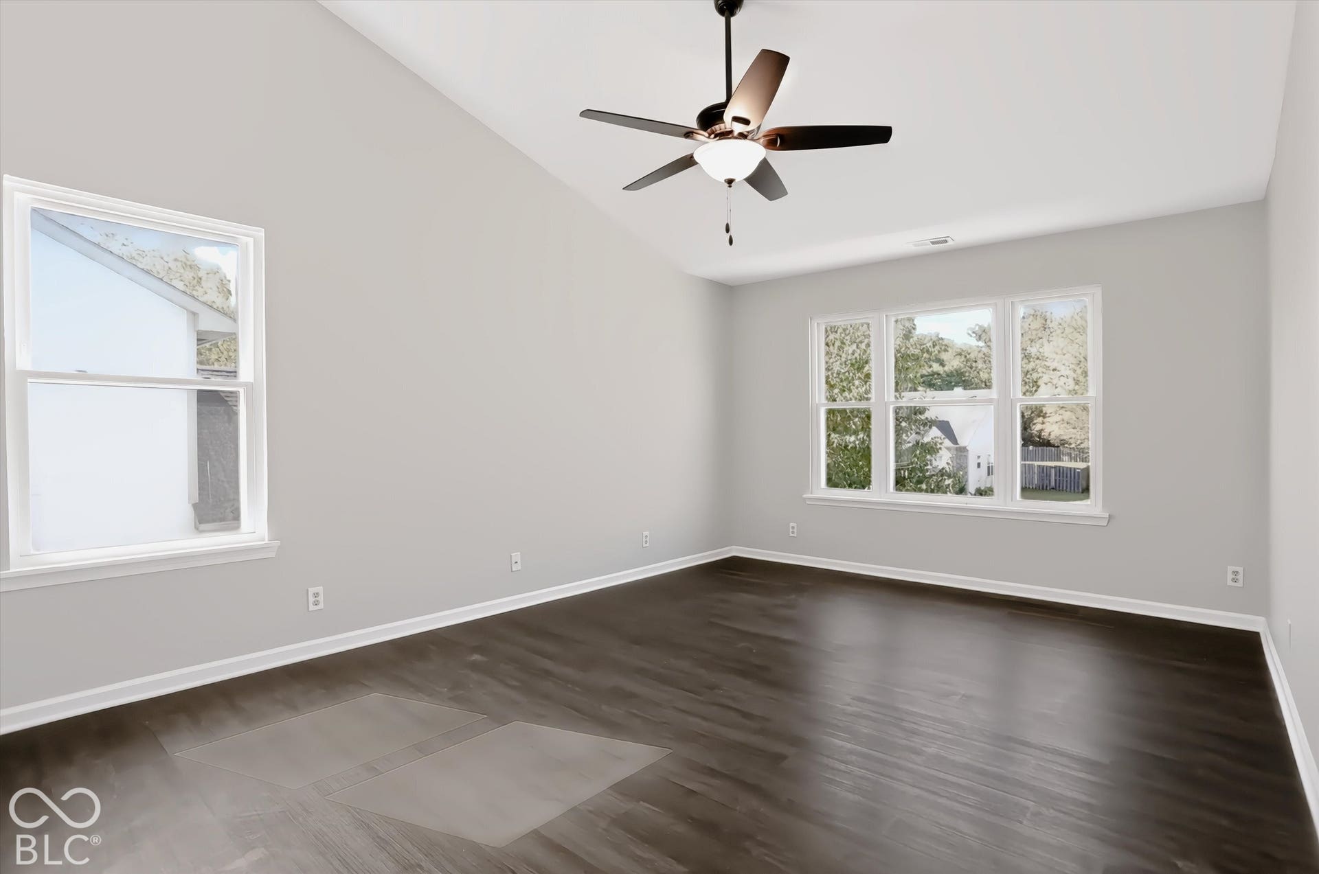 Vaulted ceiling, ceiling fan with integrated lighting, wood-finish flooring, multiple windows, neutral wall color