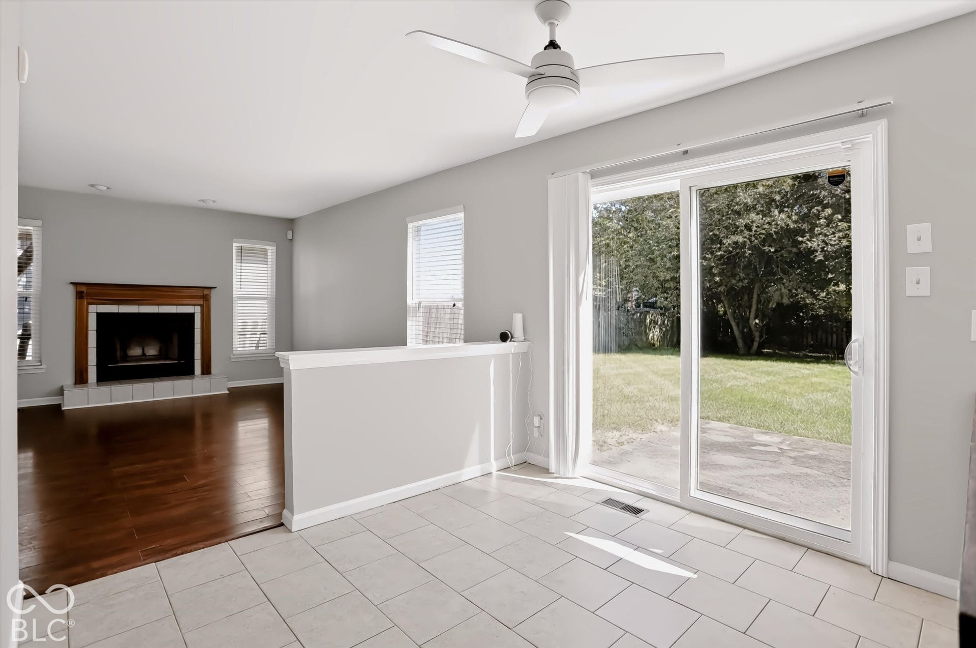 Expansive room featuring a fireplace with a wood mantel, wood-finish flooring, and white tile flooring