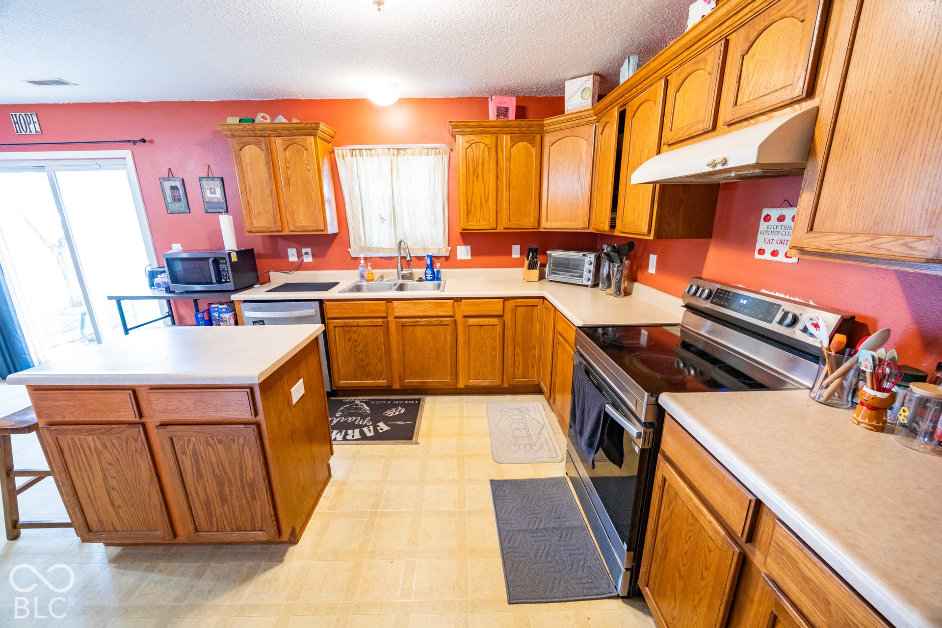 Kitchen featuring a built-in dishwasher, stainless steel oven with cooktop, wood-finish cabinetry, and light-toned countertops