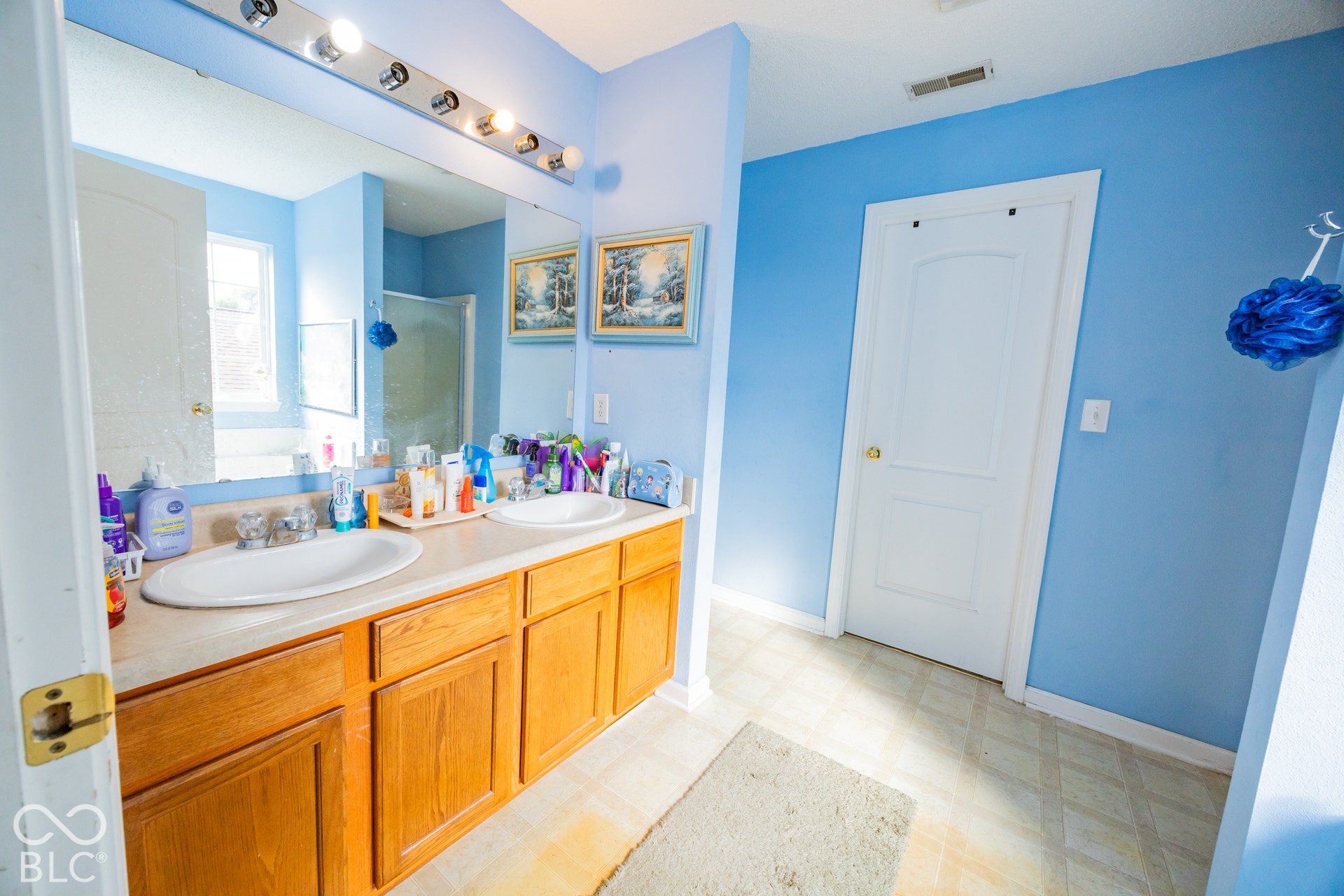 Double vanity featuring two undermount sinks, wood-finish cabinetry, and a full-width mirror