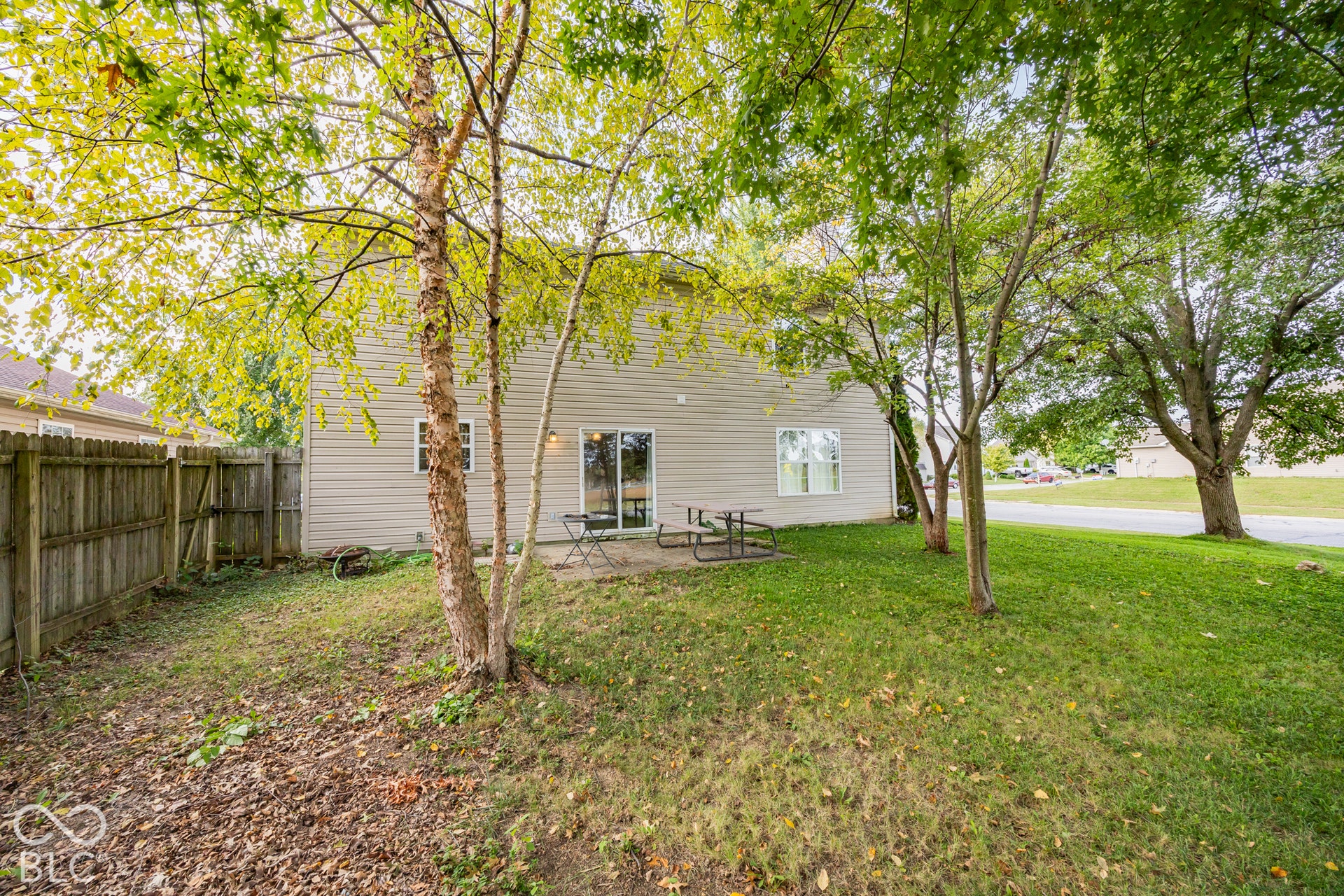 Rear exterior featuring light-colored siding, a sliding glass door, and a ground-level patio
