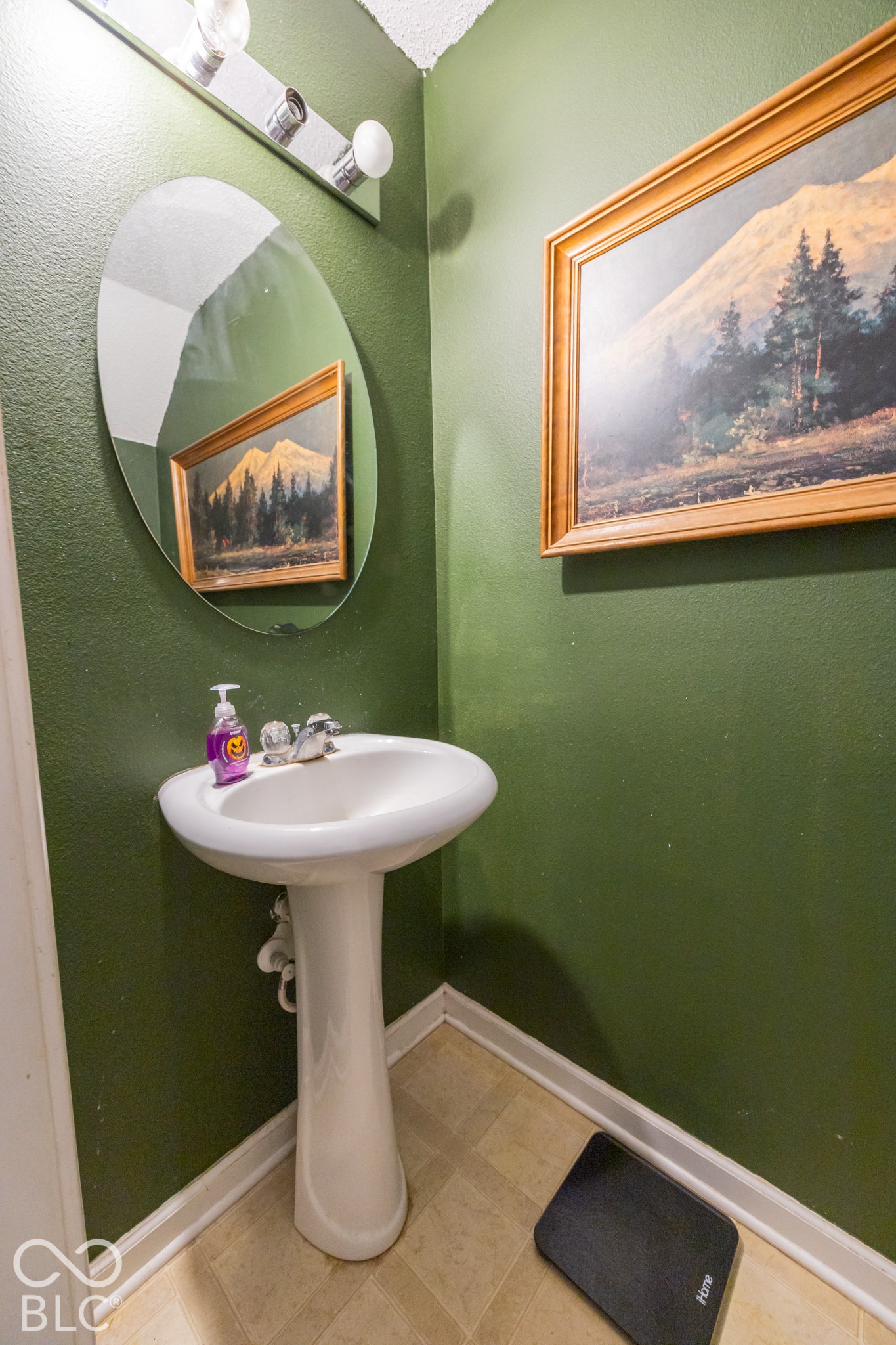 Pedestal sink with chrome fixtures and an oval wall mirror