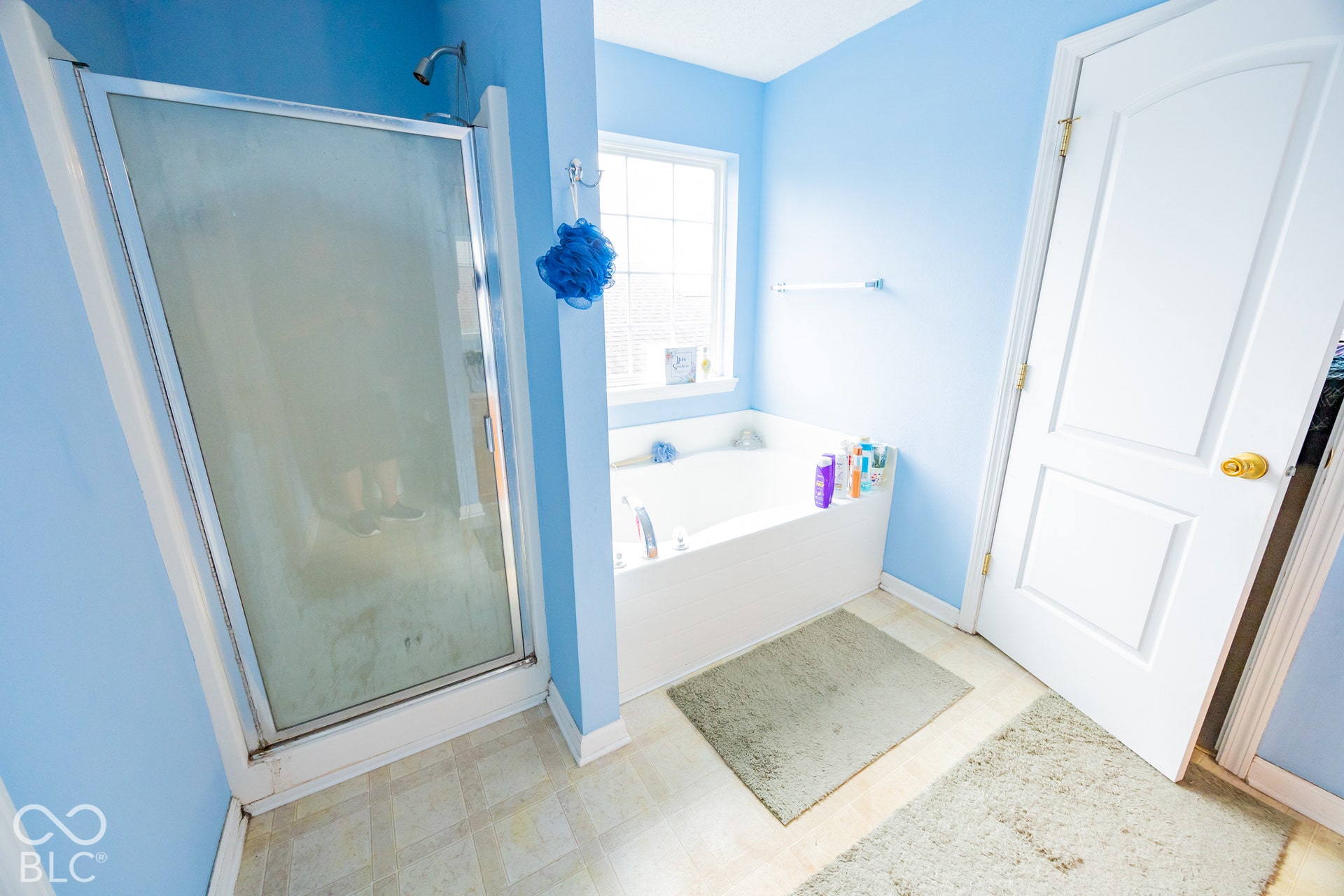 Walk-in shower with a glass enclosure, built-in bathtub, and window with natural light