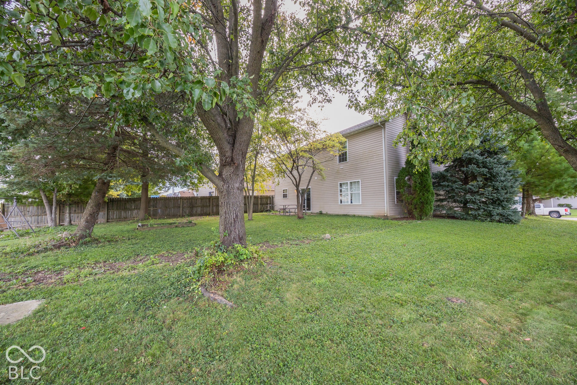 Expansive yard featuring mature trees, a manicured lawn, and a privacy fence