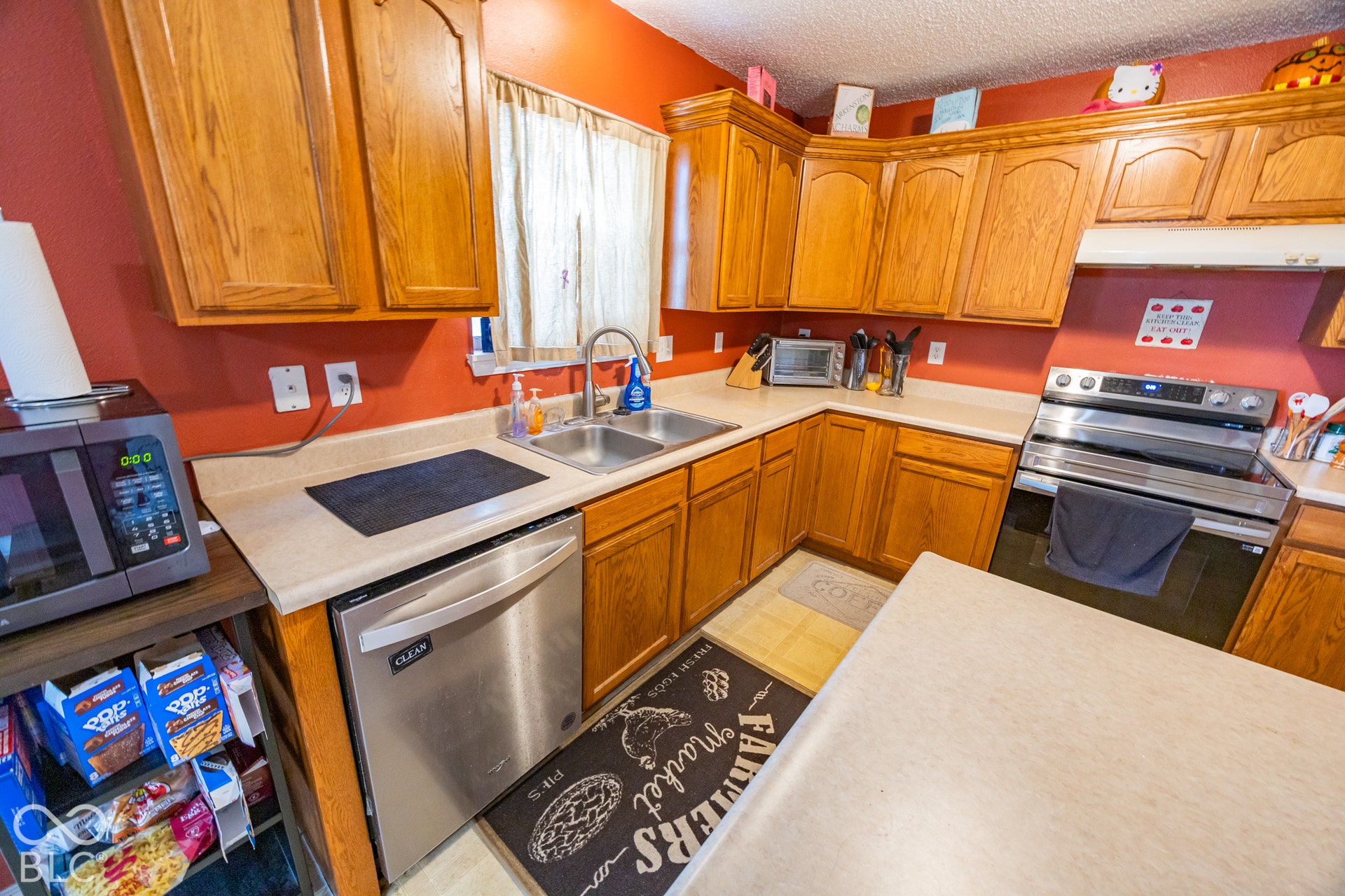 Kitchen featuring wood cabinetry, a stainless steel dishwasher, a stainless steel range, and a dual basin sink