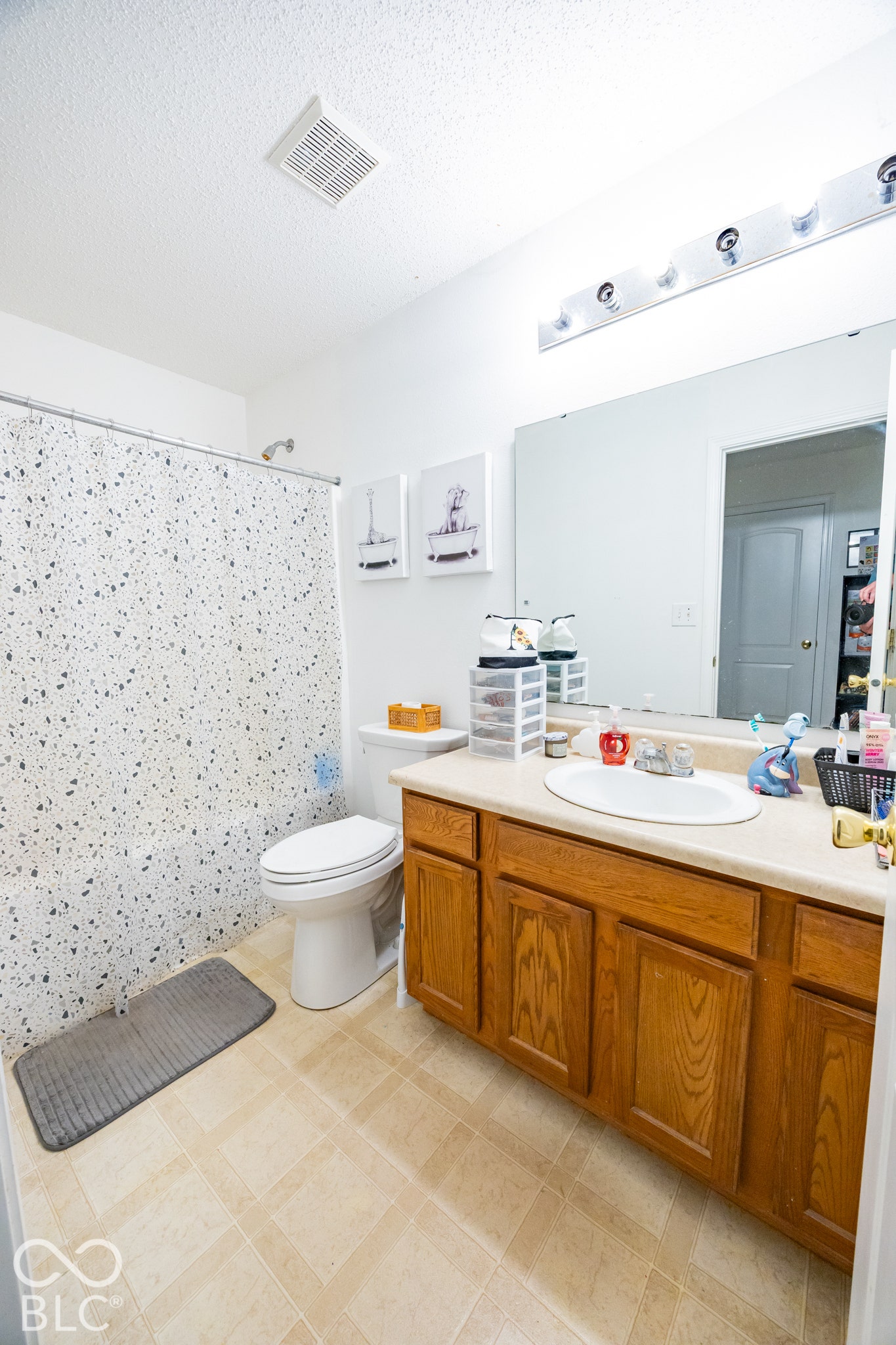 Bathroom with a wood-finish vanity, integrated sink, and a large wall-mounted mirror