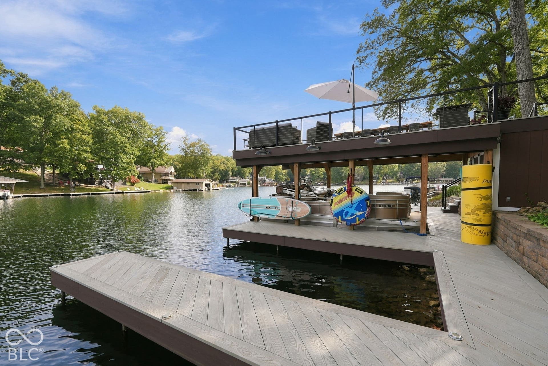 Multi-level dock with composite decking, upper deck with black railings, and a covered lower level with a built-in spa