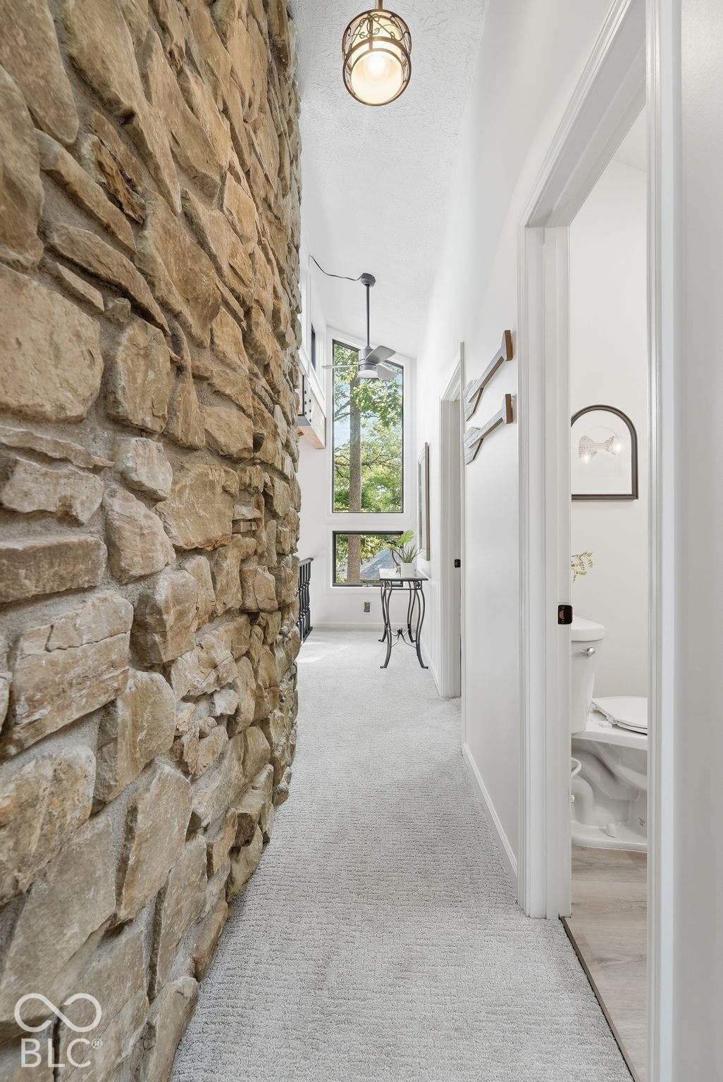 Stone accent wall, vaulted ceiling, large picture windows, recessed lighting, and carpet flooring