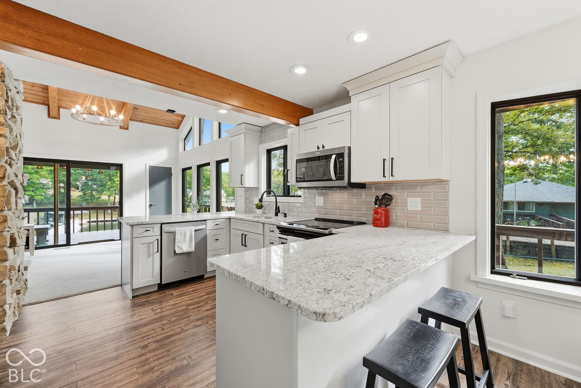 Kitchen featuring wood-finish flooring, white cabinetry, integrated stainless steel appliances, light-toned countertops, and a subway tile backsplash
