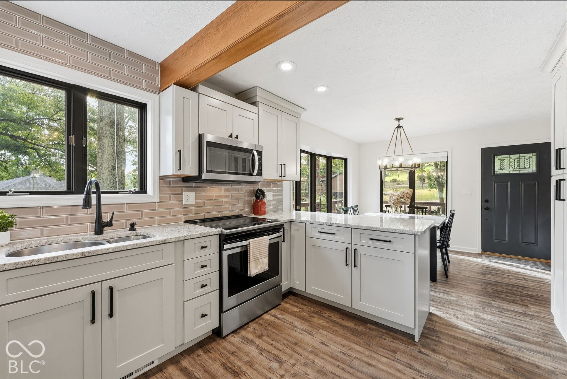 Kitchen featuring light-colored cabinetry, stainless steel appliances, a light-toned countertop, and wood-finish flooring