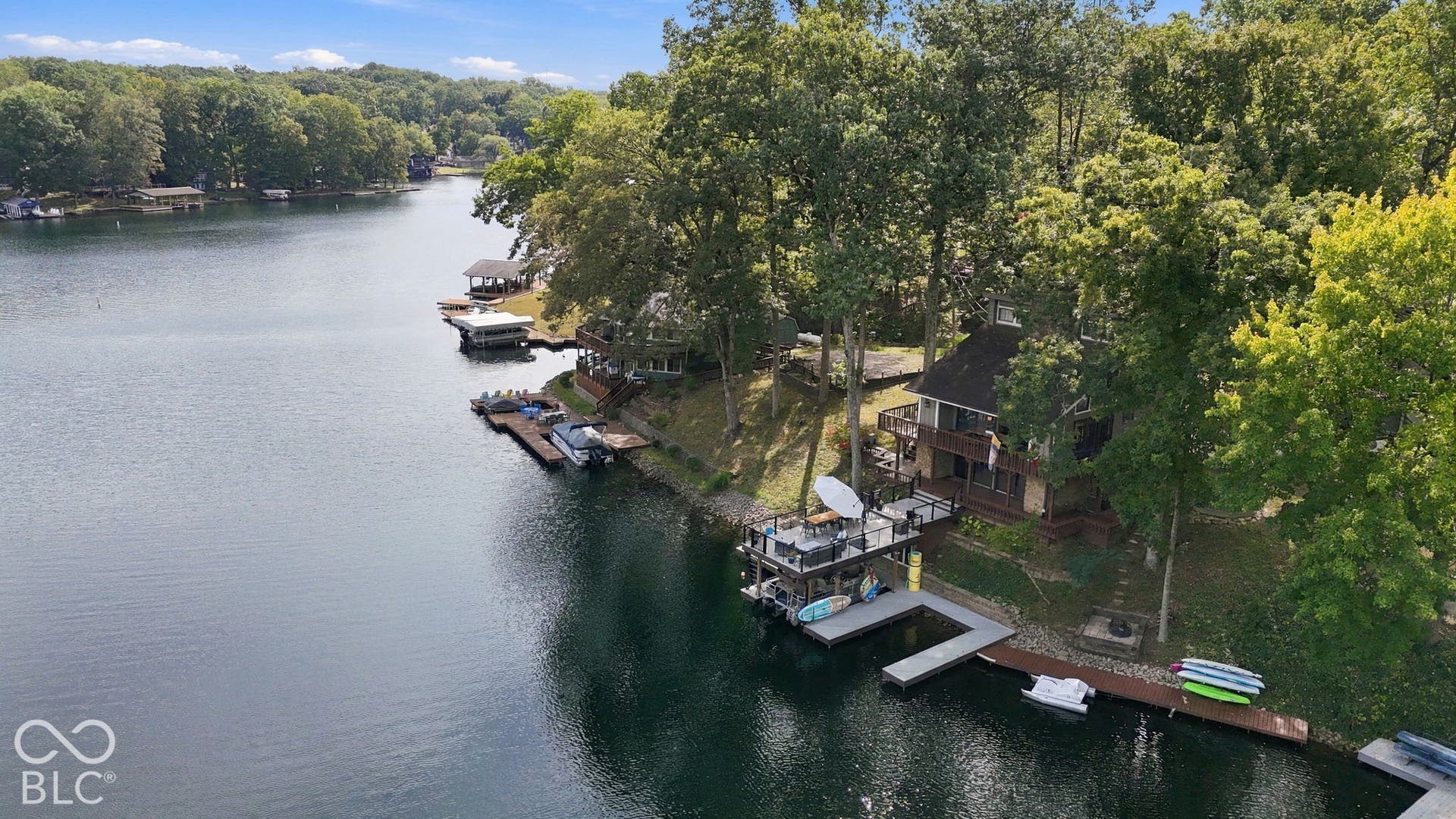Waterfront property featuring a multi-level dock, an elevated deck, and mature trees