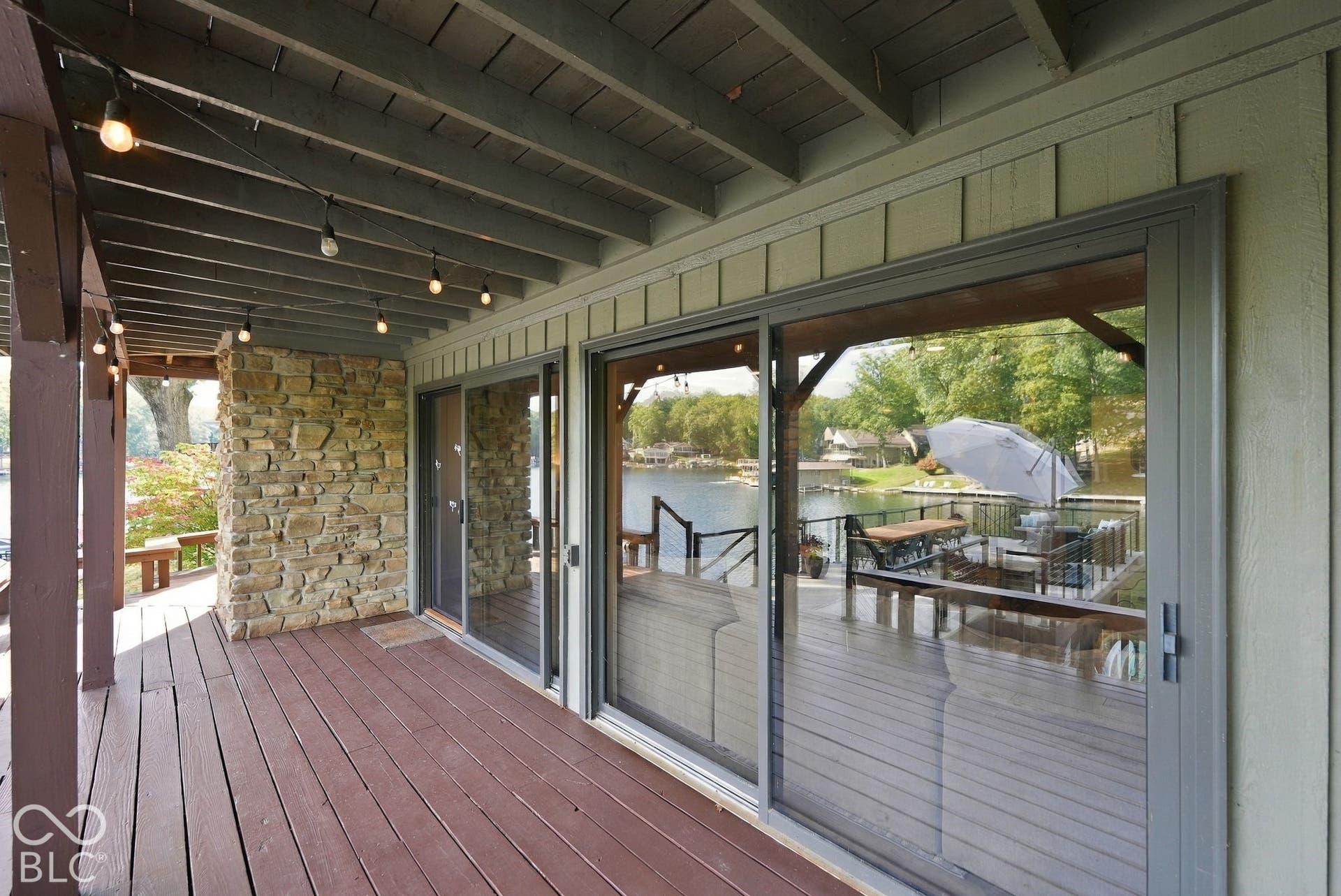 Expansive covered deck featuring a stone wall accent and wood-finish flooring