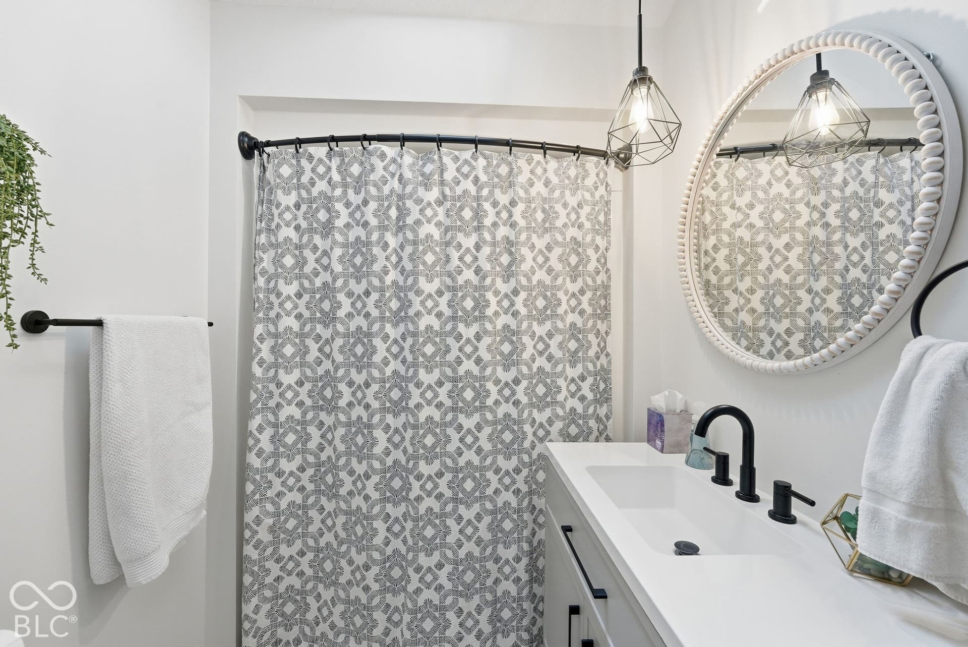 White vanity with an integrated rectangular sink, matte black faucet, and pendant lighting