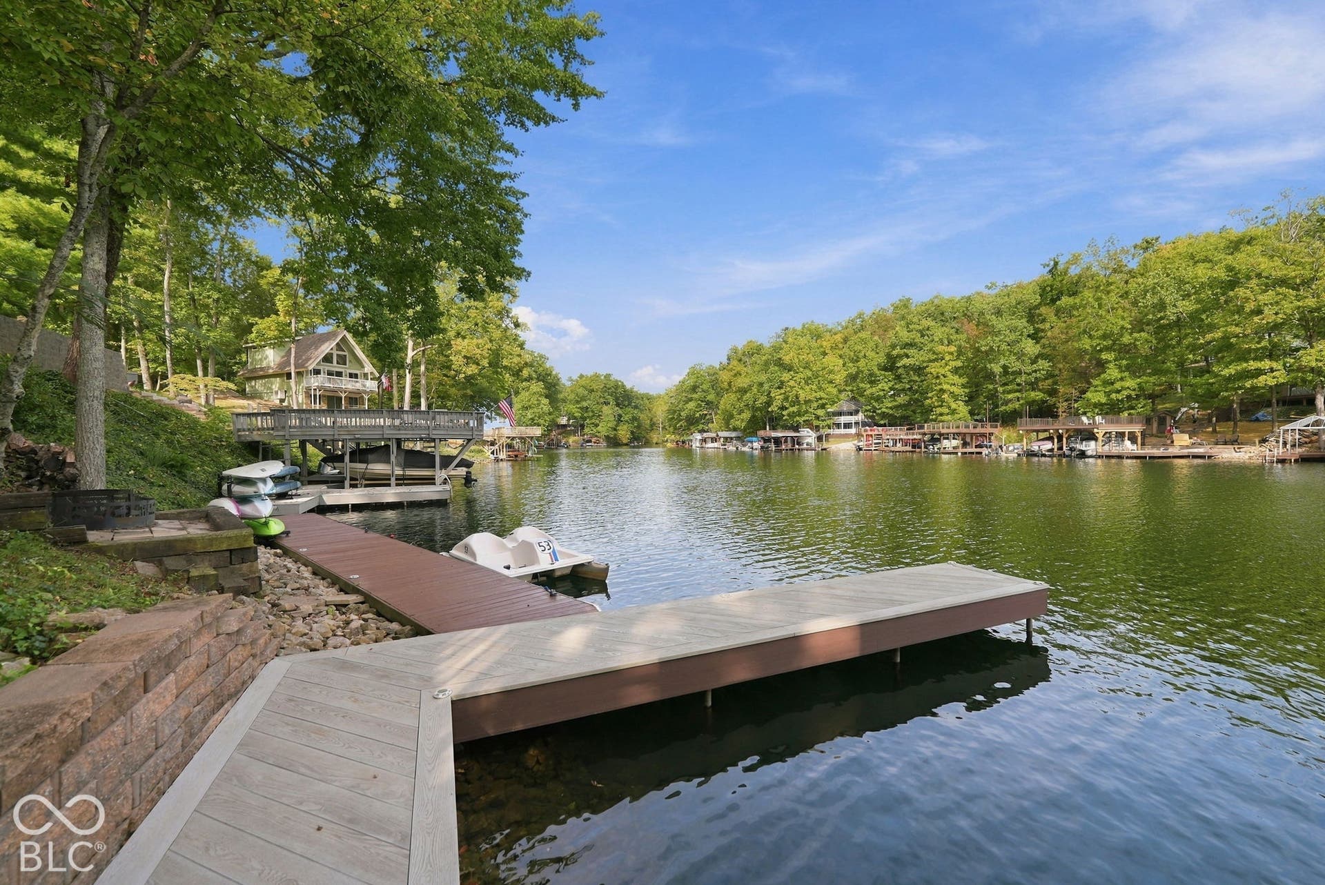 Lakefront property featuring a private dock, boat slip, and retaining wall along the shoreline