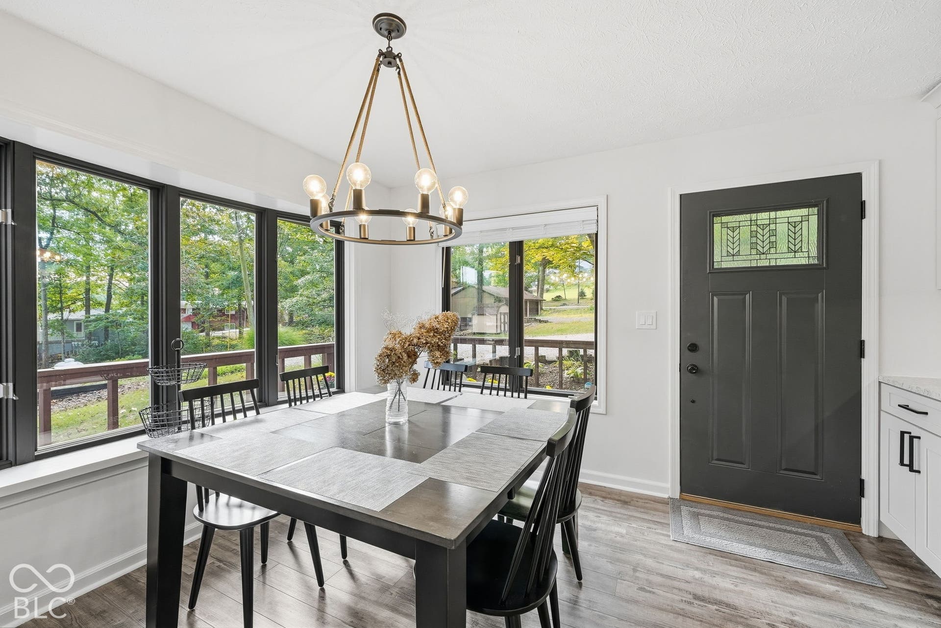 Spacious dining area featuring large windows, wood-finish flooring, and an elegant chandelier