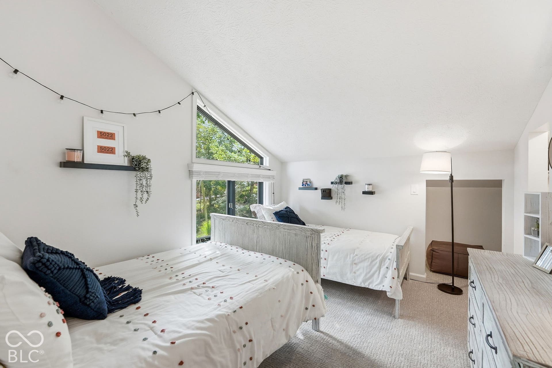 Angled ceiling with an integrated triangular window, additional transom window, and textured carpeting