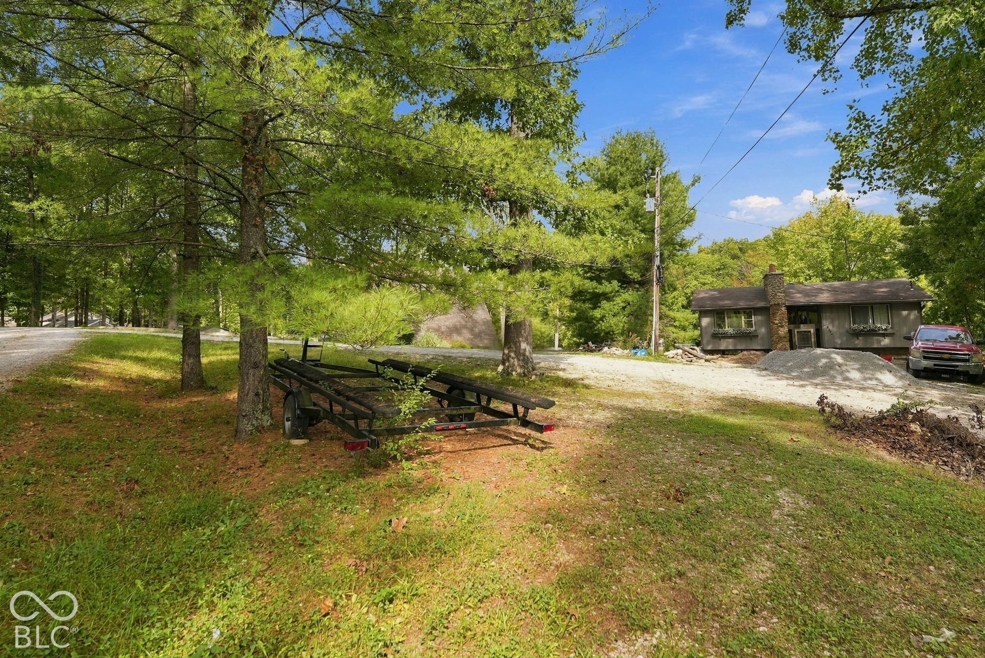 Single-story residence featuring a stone chimney and gravel driveway