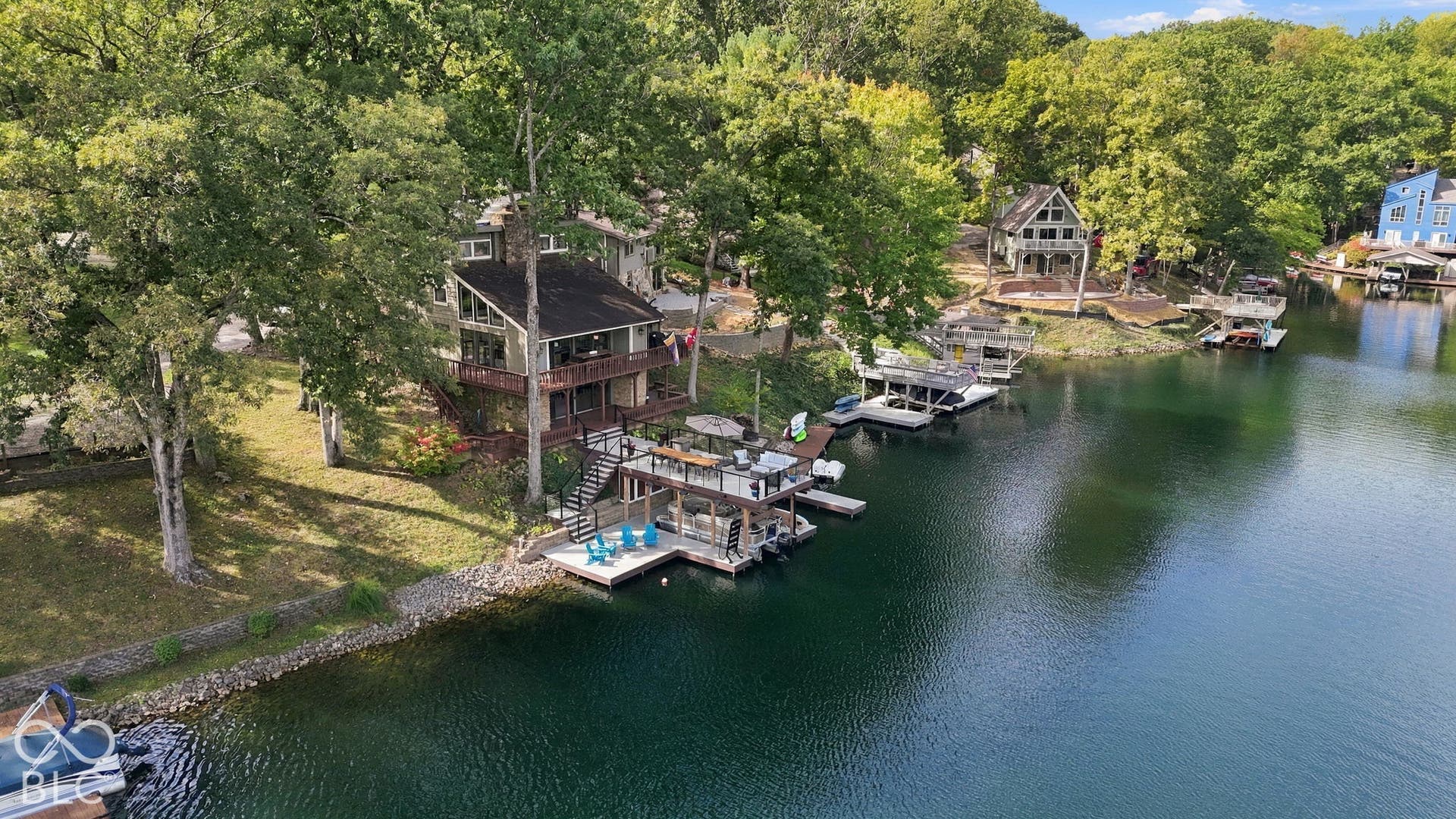 Waterfront property featuring a multi-level dwelling, expansive decking, a private boat dock, and mature trees