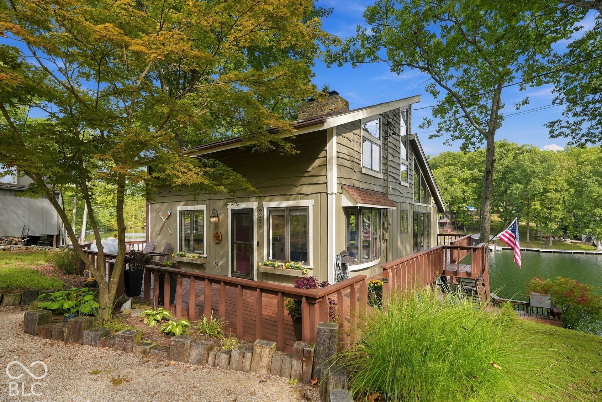 Exterior featuring a wood deck with railings, water frontage, natural wood siding, and multiple windows