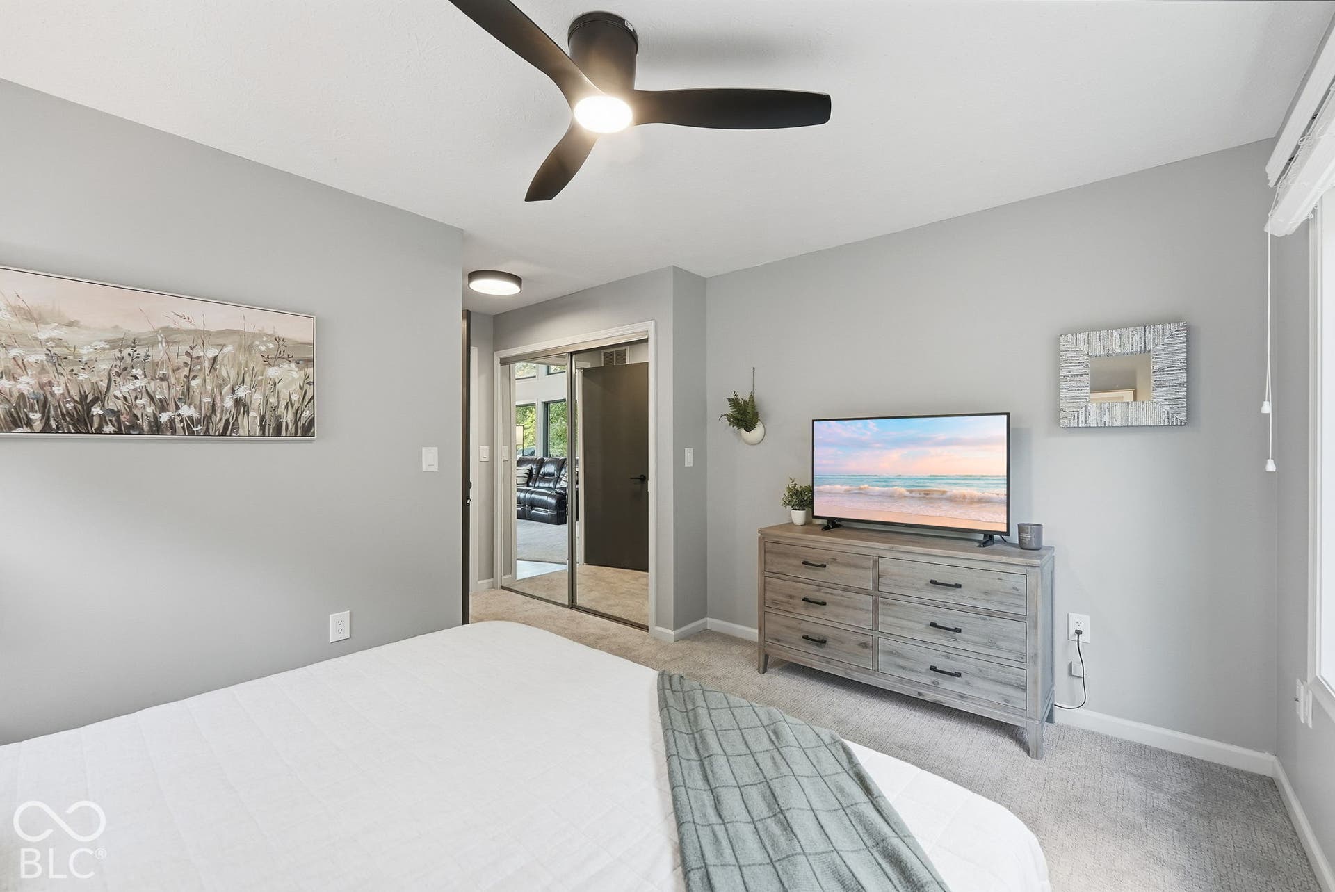 Ceiling fan with integrated light fixture, light gray wall paint, carpeted flooring, window with blinds, and mirrored sliding closet doors