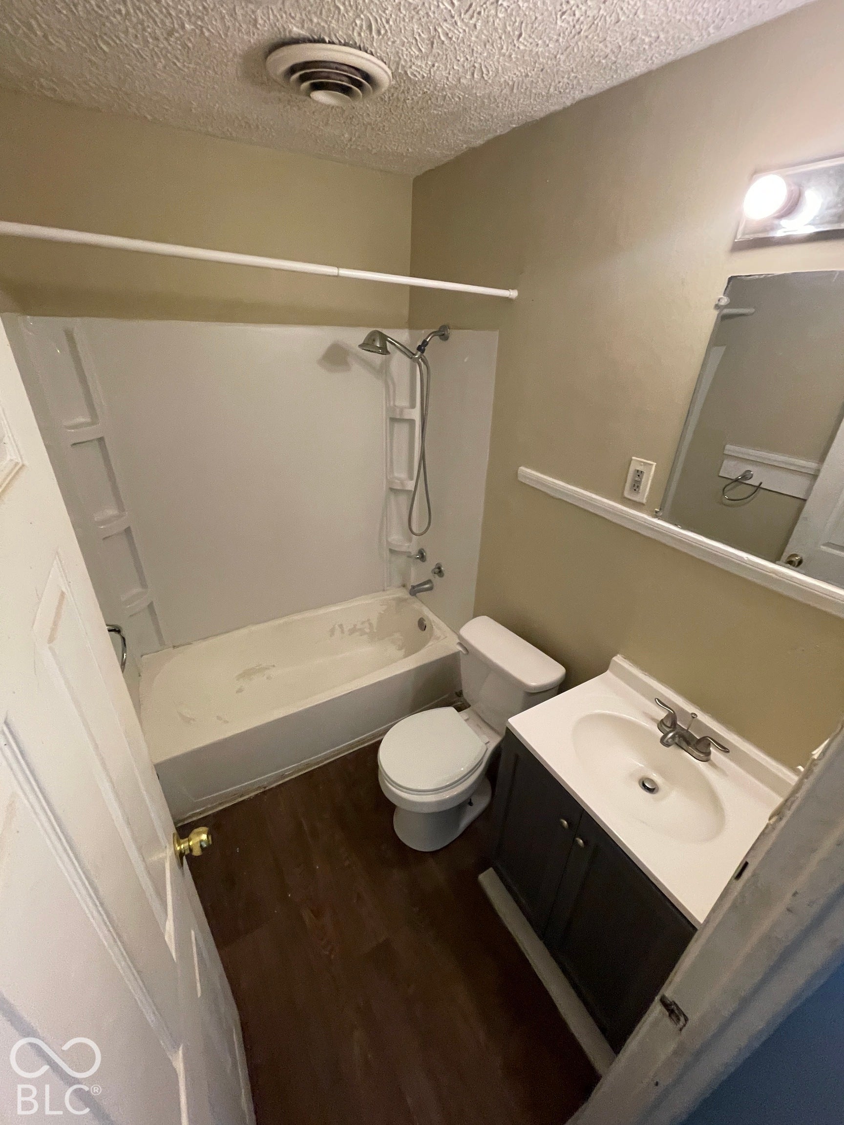 Wood-finish flooring with a white bathtub and shower combination