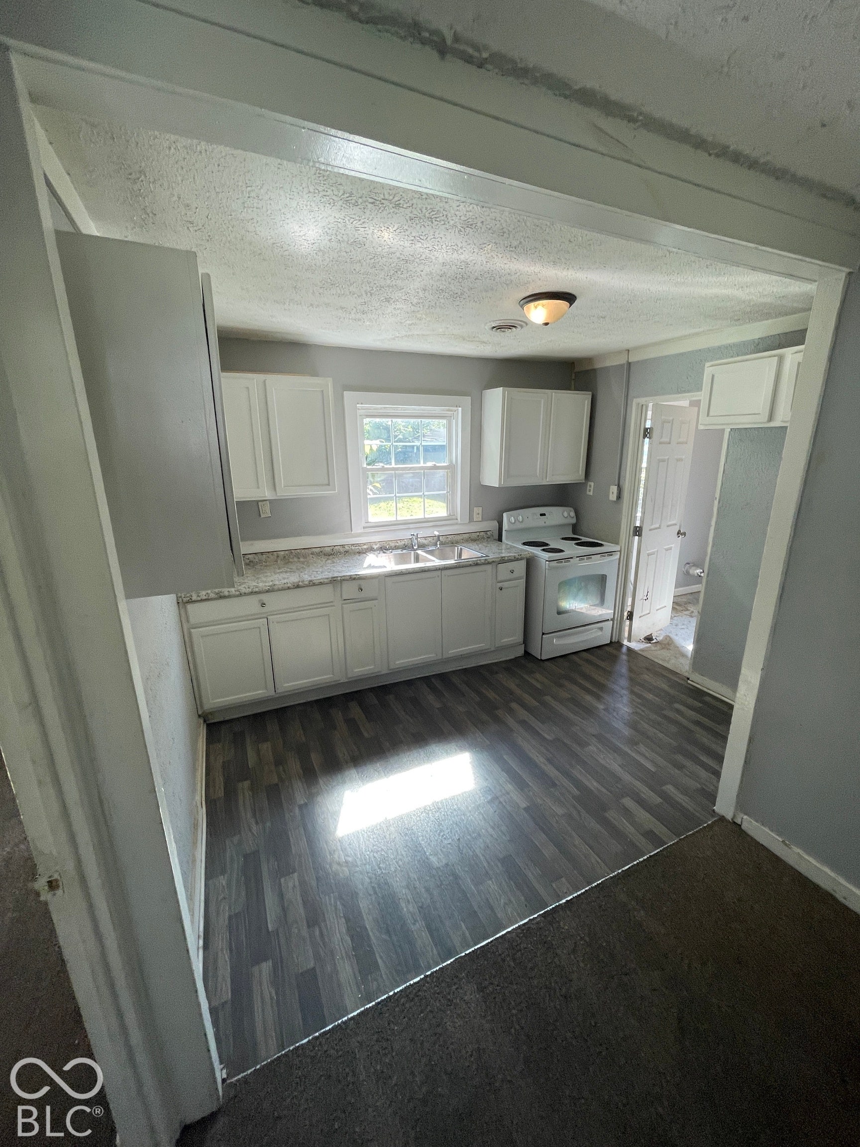 Kitchen featuring white cabinetry, wood-finish flooring, white appliances, and a window above the sink