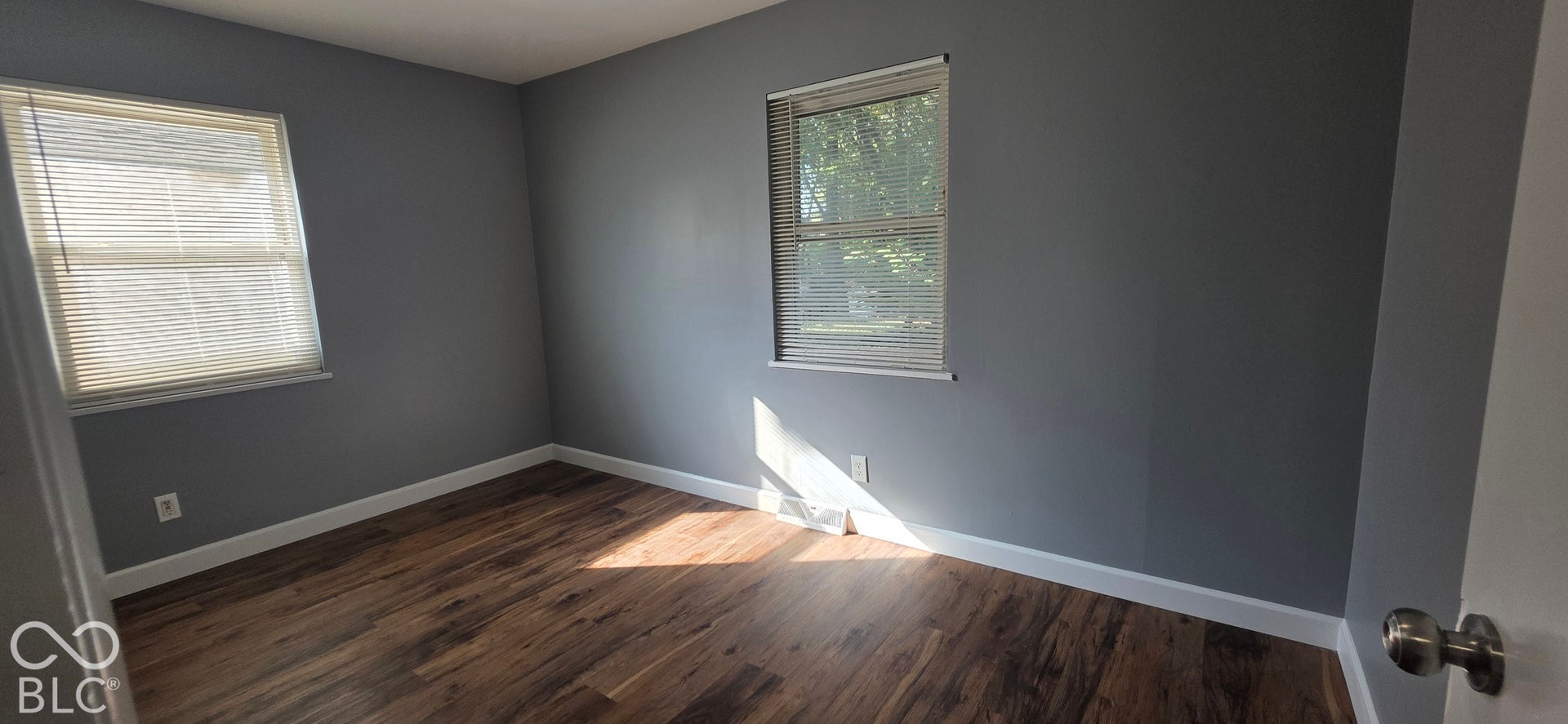 Wood-finish flooring with white trim and grey walls