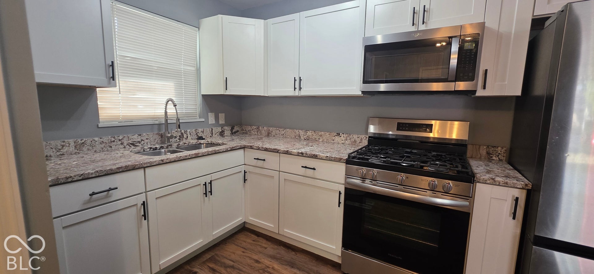 Kitchen featuring white cabinetry, light-toned countertops, a stainless steel range, a stainless steel microwave, and wood-finish flooring