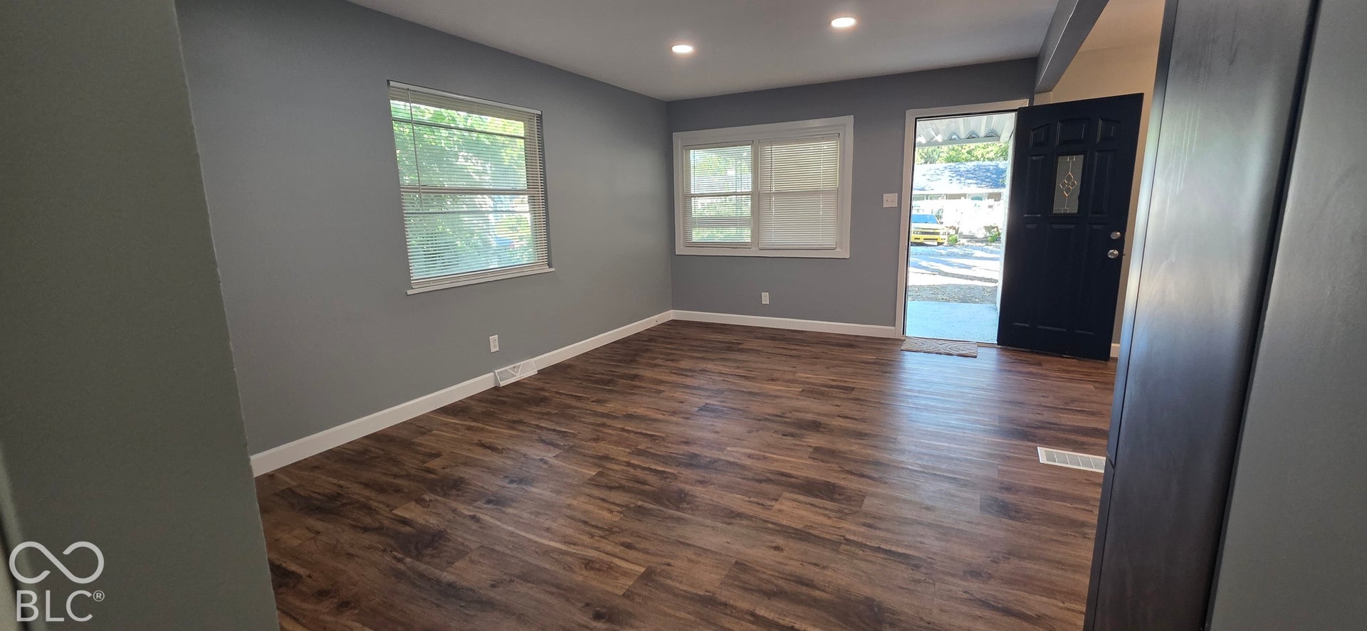 Wood-finish flooring, recessed lighting, and a dark-paneled entry door with decorative glass