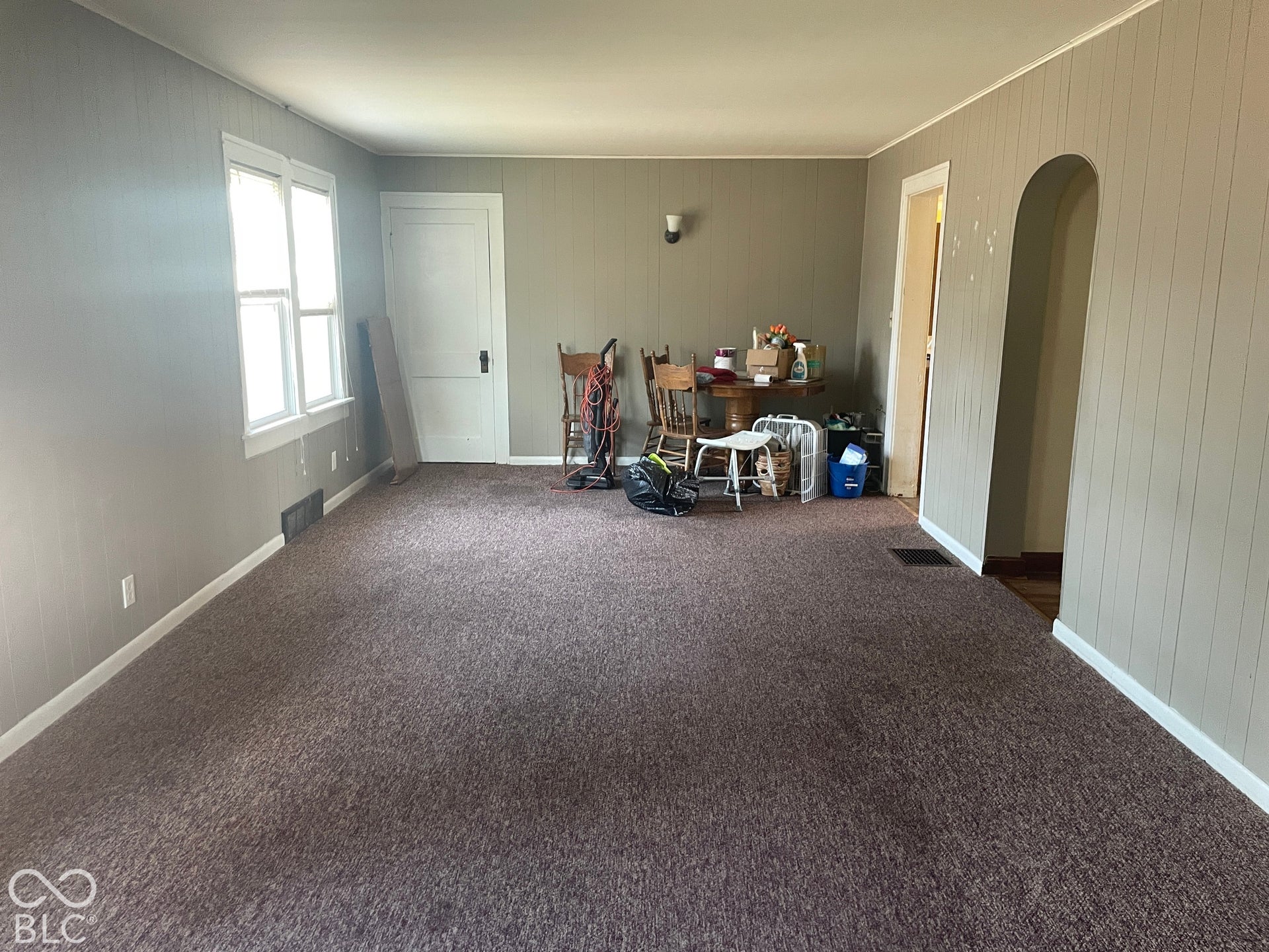 Wall paneling, white trim, arched doorway, and carpeted flooring