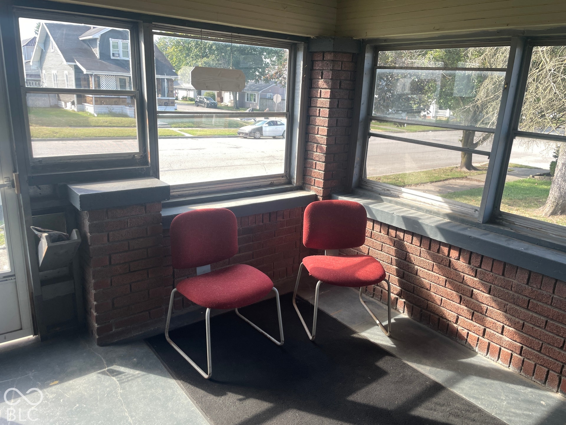 Enclosed porch with brick half-walls, multiple windows, and slate-finish flooring
