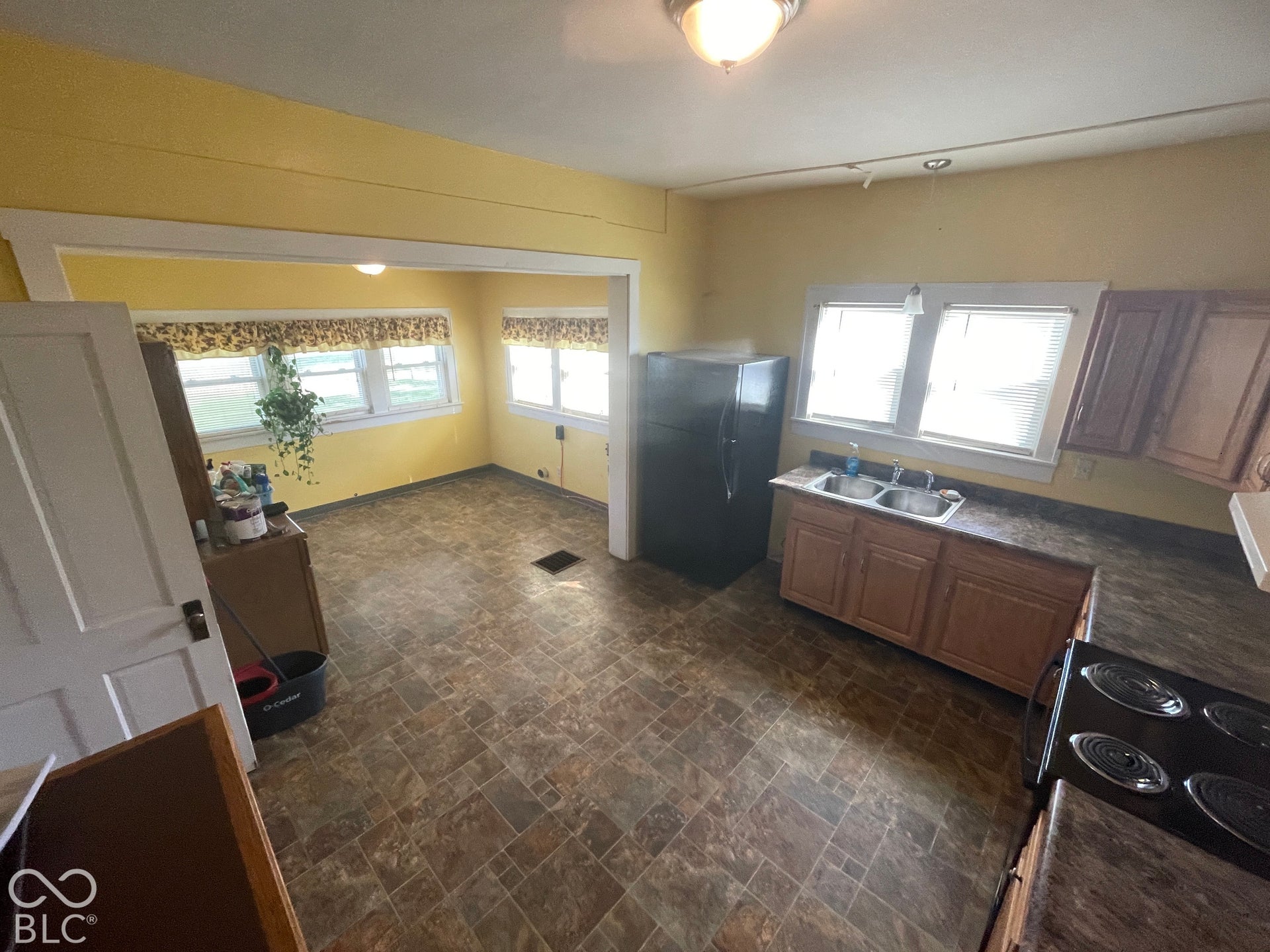 Kitchen area featuring a double basin sink, upper and lower cabinetry, and resilient flooring