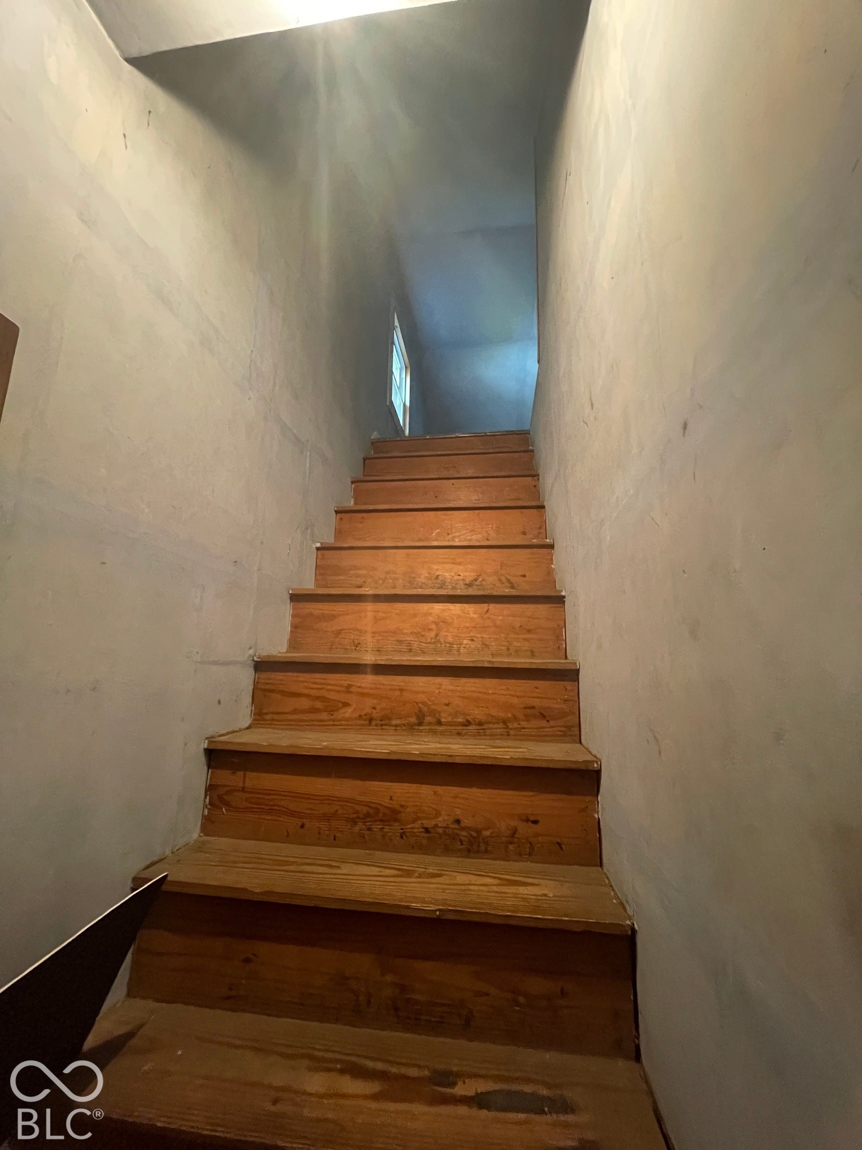 Wood-finish staircase with natural light from an upper window