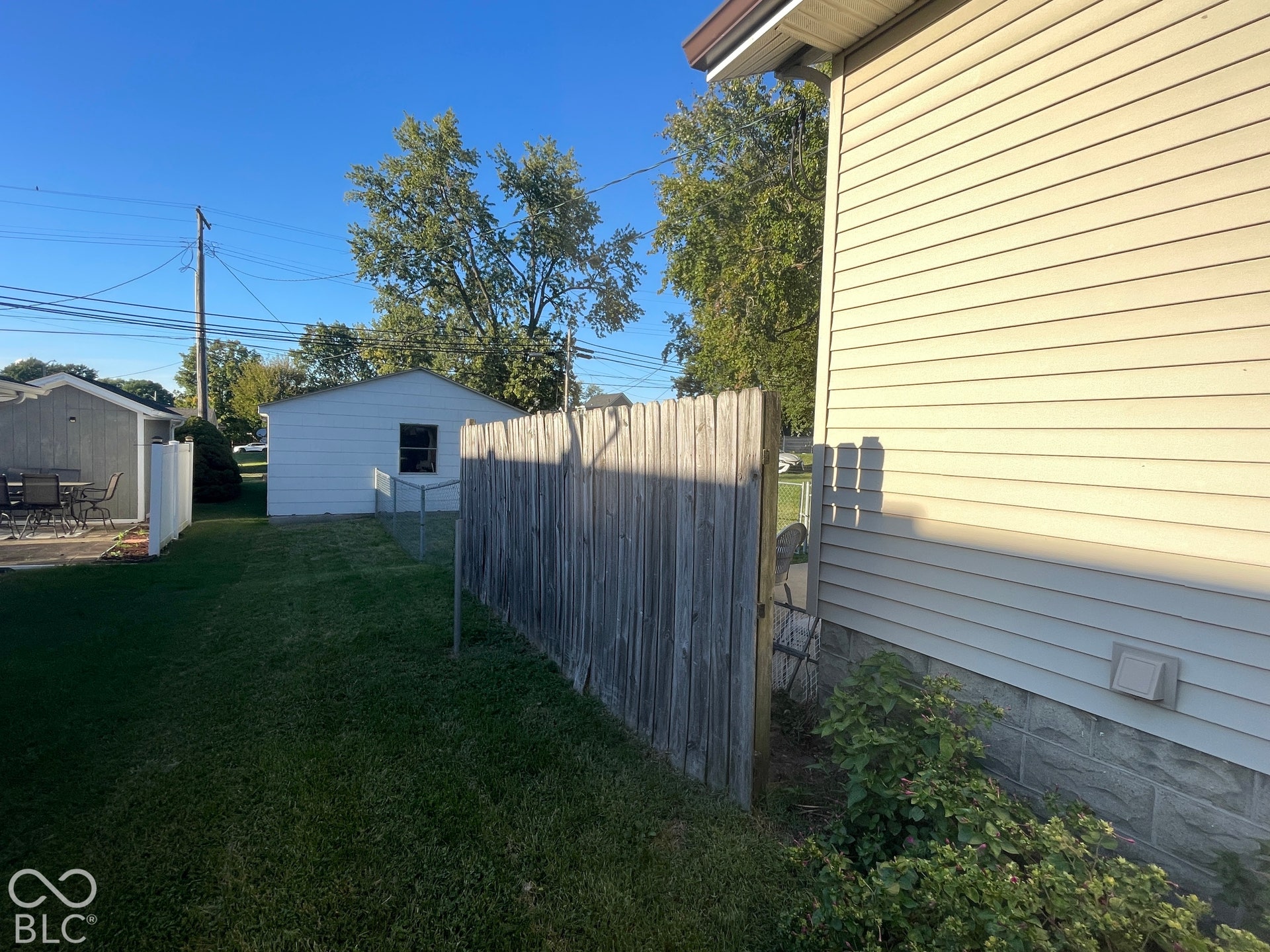 Expansive green lawn with a wood fence and chain link fence