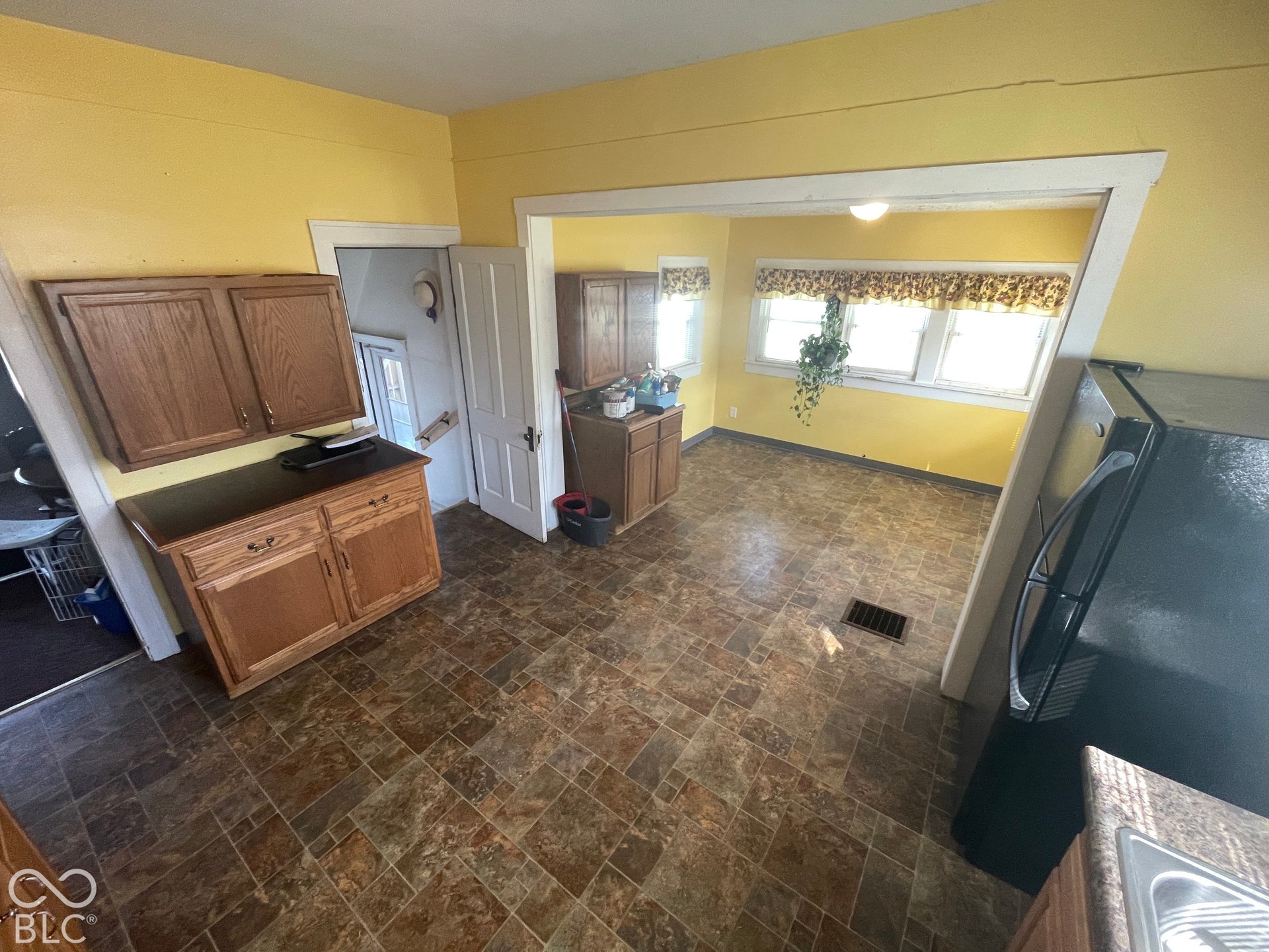 Kitchen area featuring wood-finish cabinetry, patterned floor tiling, and a separate dining area with multiple windows