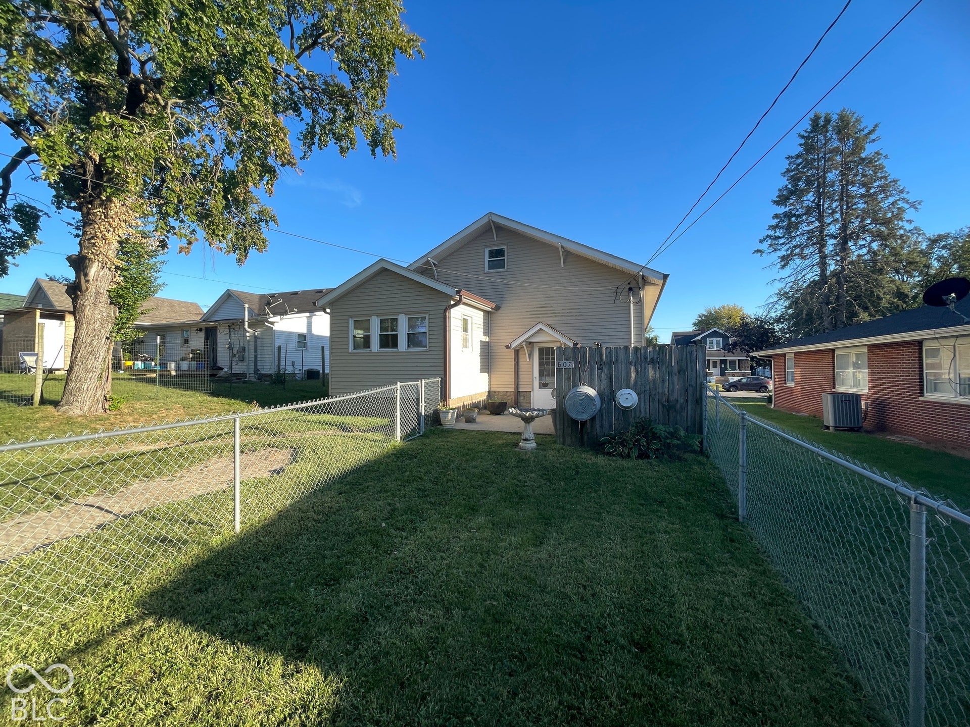 Expansive chain-link fenced yard featuring a well-maintained lawn and established trees