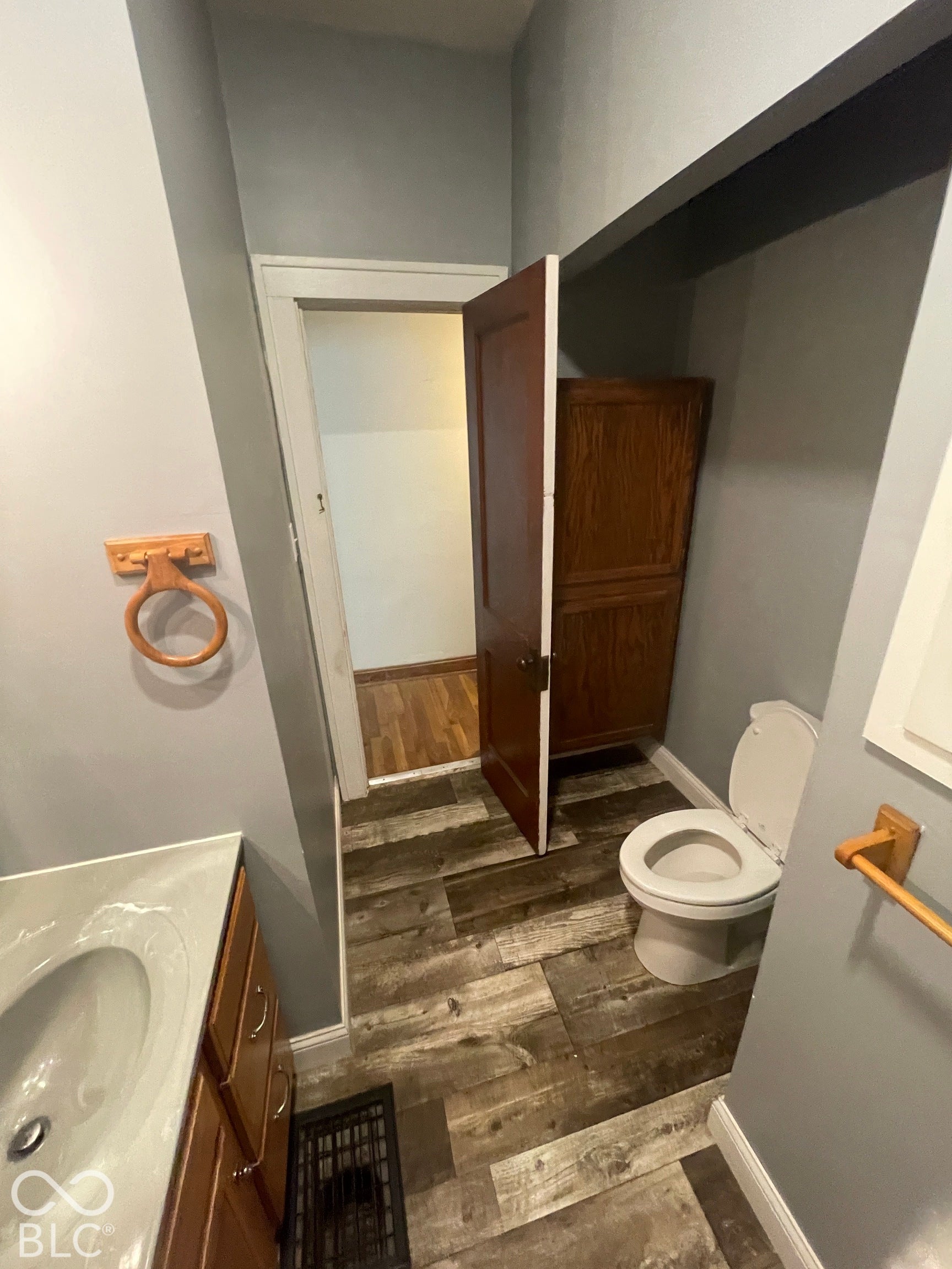 Wood-finish flooring throughout, vanity with integrated sink, wooden cabinetry, and a built-in storage cabinet