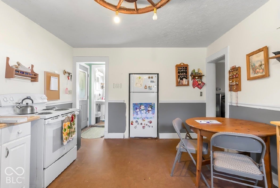 Kitchen area with painted white cabinetry, white range, and wood-finish flooring