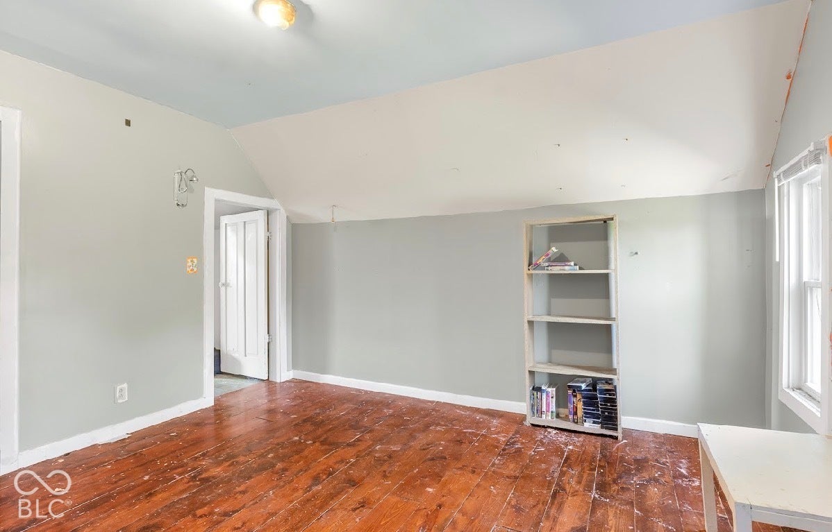 Wood-finish flooring with white trim, light gray walls, built-in shelving, and a recessed window