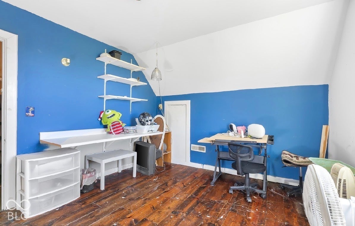Wood-finish flooring with a blue and white painted wall, featuring built-in wall shelving and a hanging light fixture