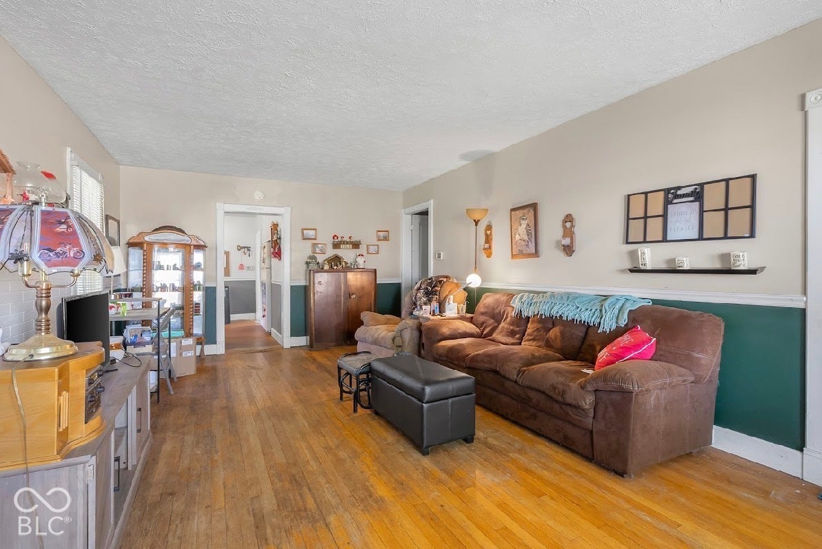 Hardwood flooring throughout, neutral tone walls with contrasting lower wall paneling, and white trim accents