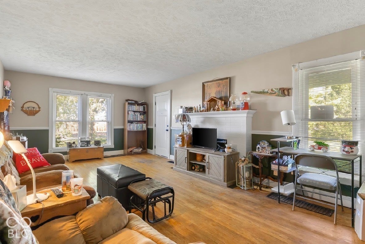 Hardwood flooring throughout, white trim molding, and a white paneled fireplace