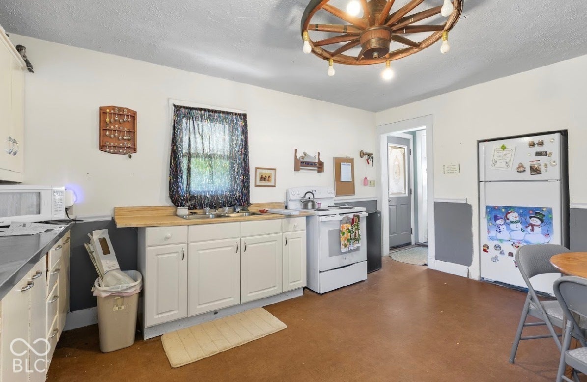 Kitchen featuring white cabinetry, light wood-finish countertops, and a ceiling-mounted wagon wheel light fixture