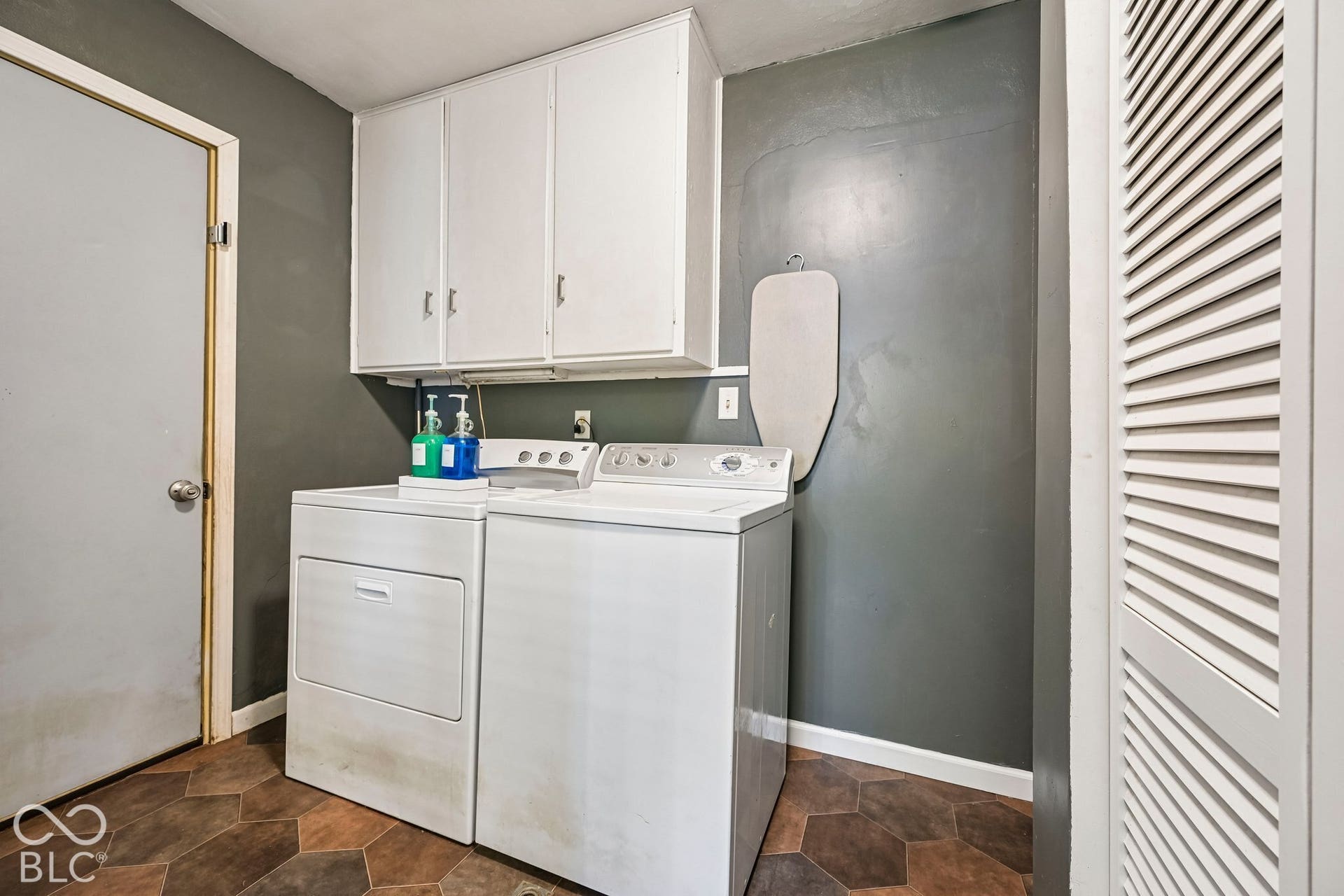 Laundry area featuring white cabinetry, a white dryer, a white washing machine, and hexagonal floor tiles