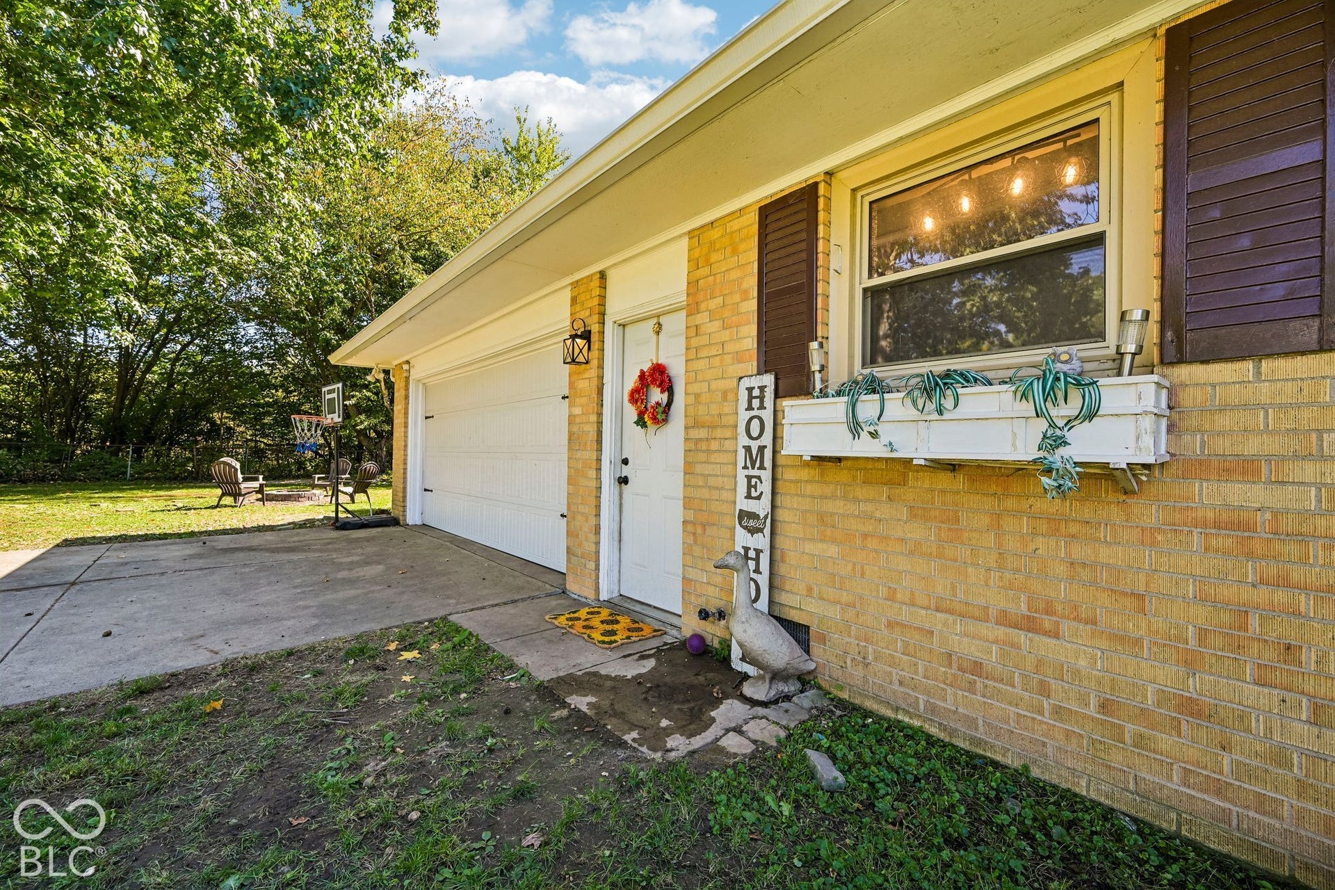 Brick exterior with dark shutters, white window box, and a two-car garage